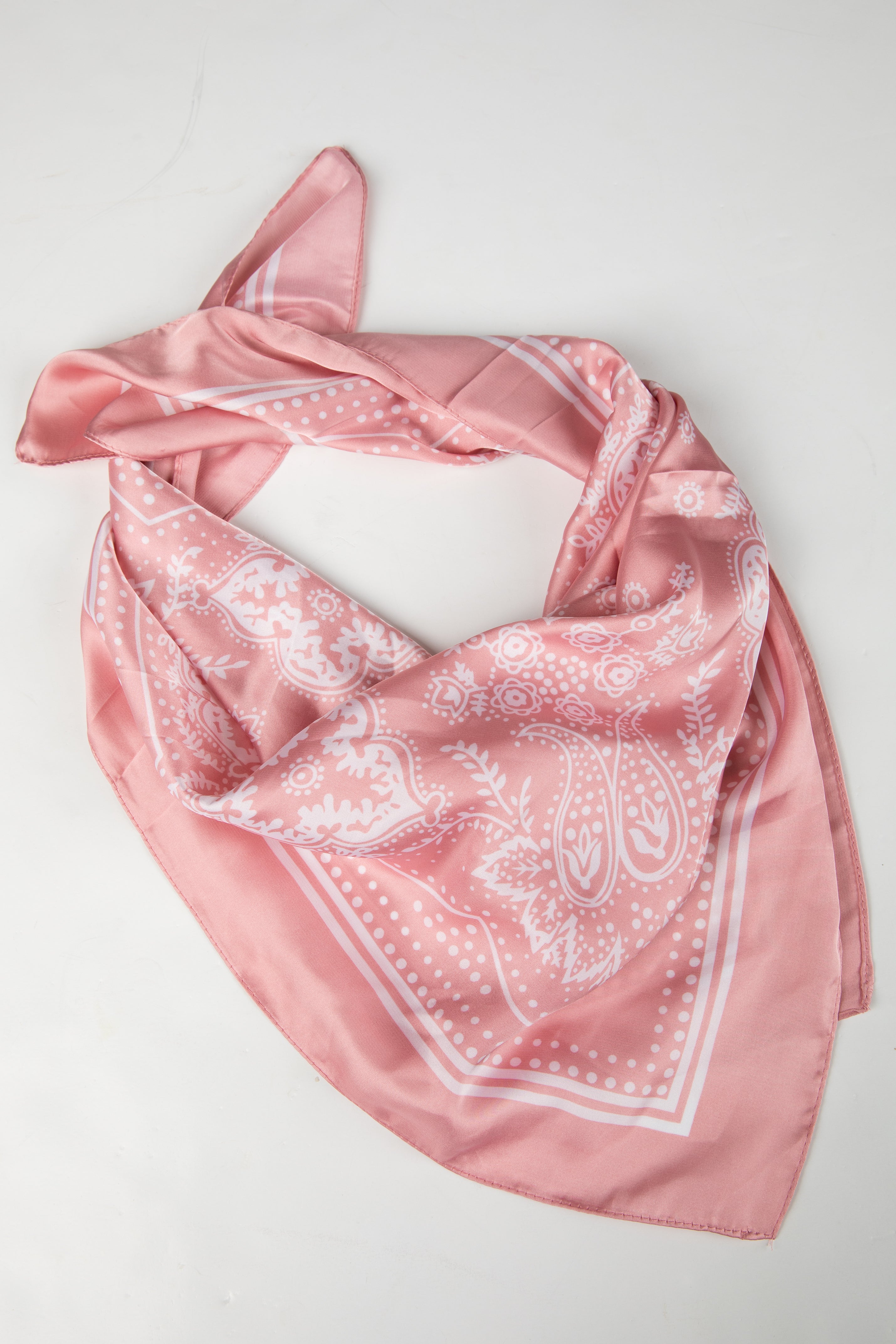 Pink bandana with white patterns on a light gray background