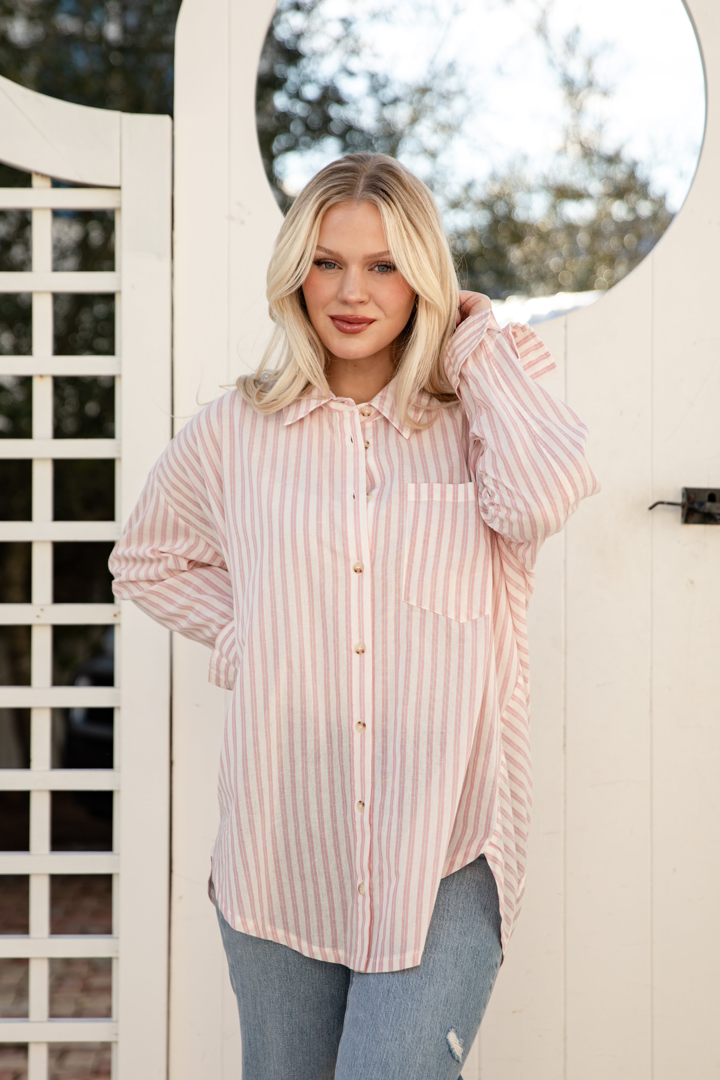 Woman wearing a pink striped shirt standing outdoors.