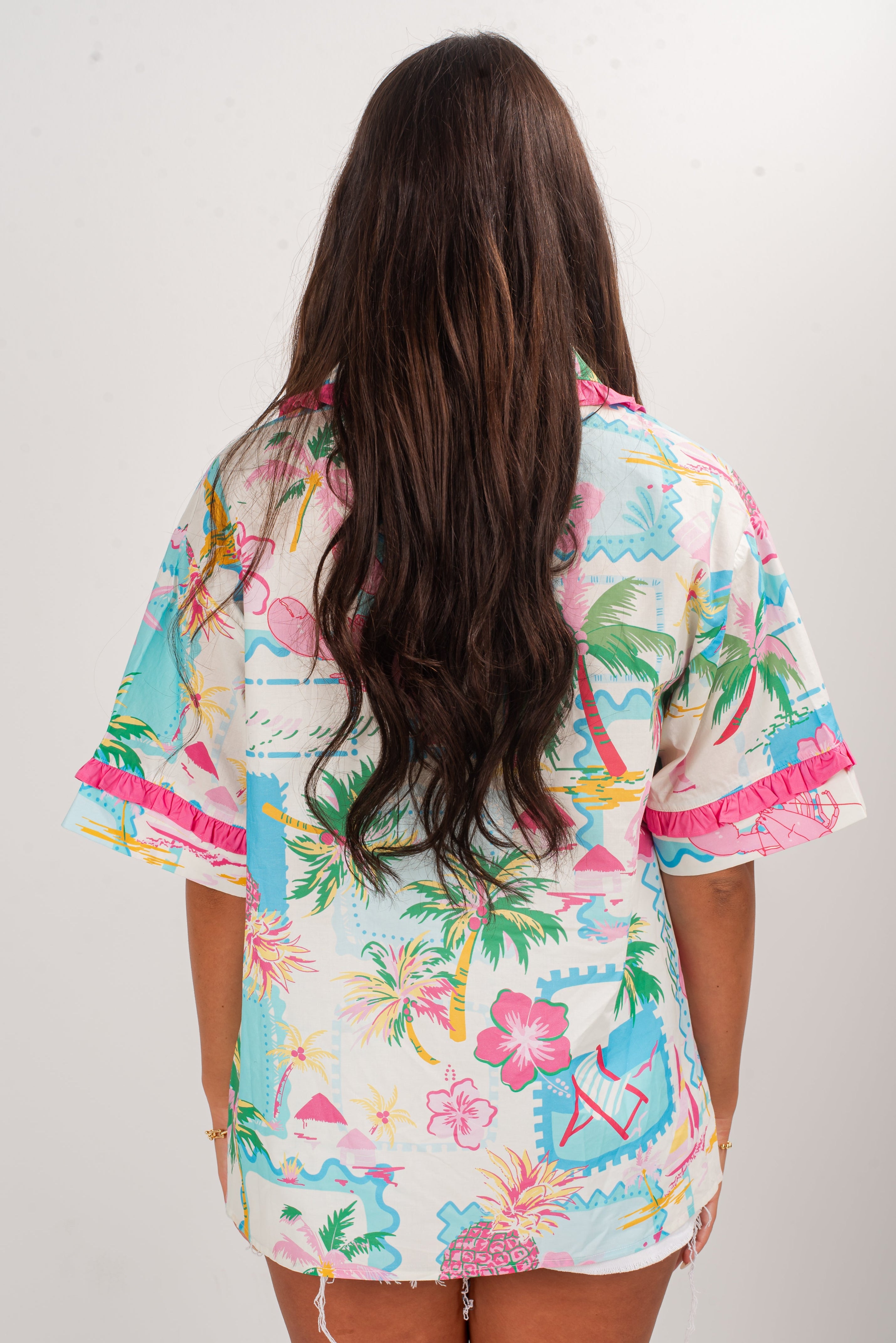 Woman wearing a colorful tropical print kimono-style garment against a white background