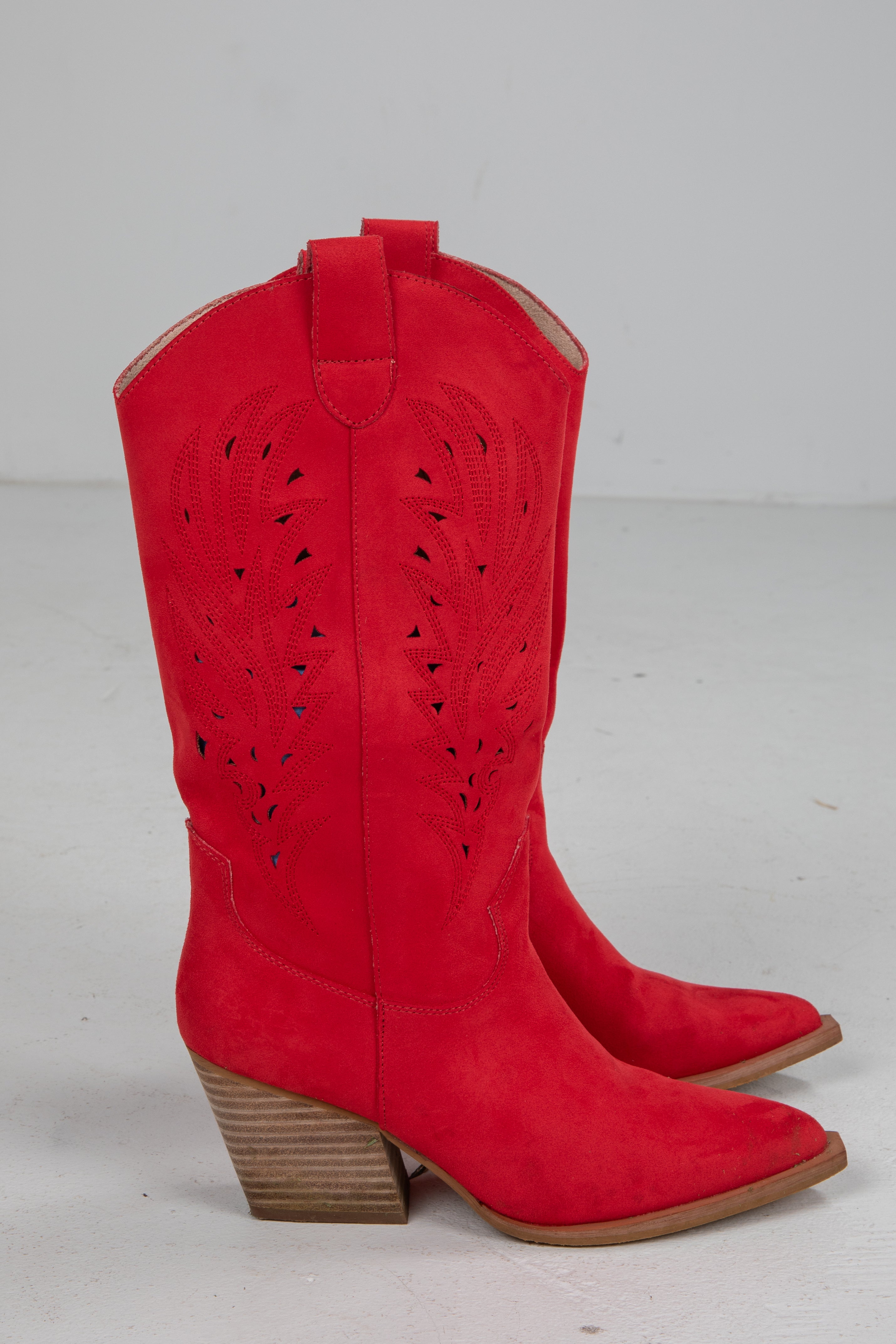 Red cowboy boots with brown soles on a light gray background