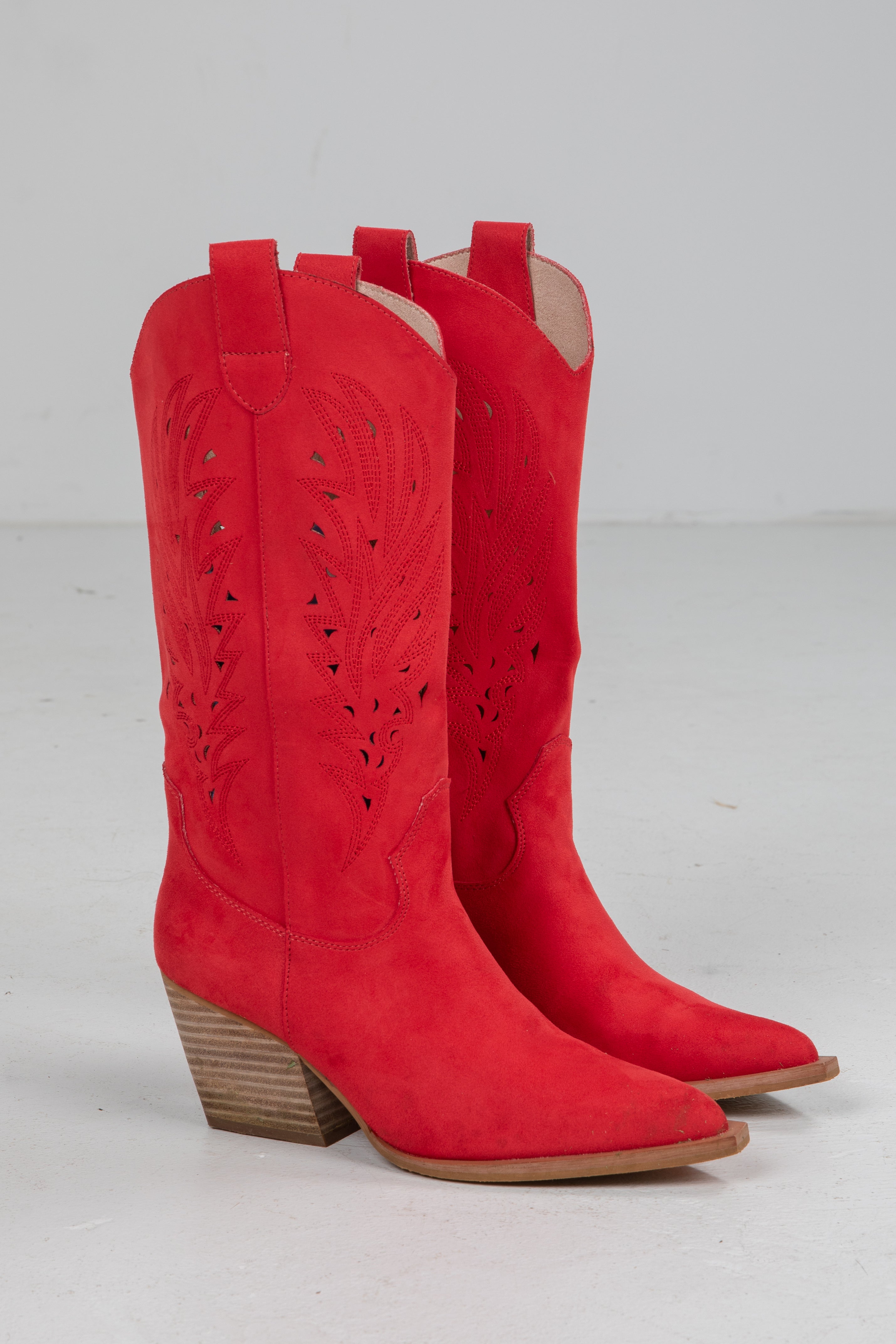 Pair of red cowboy boots on a light gray background
