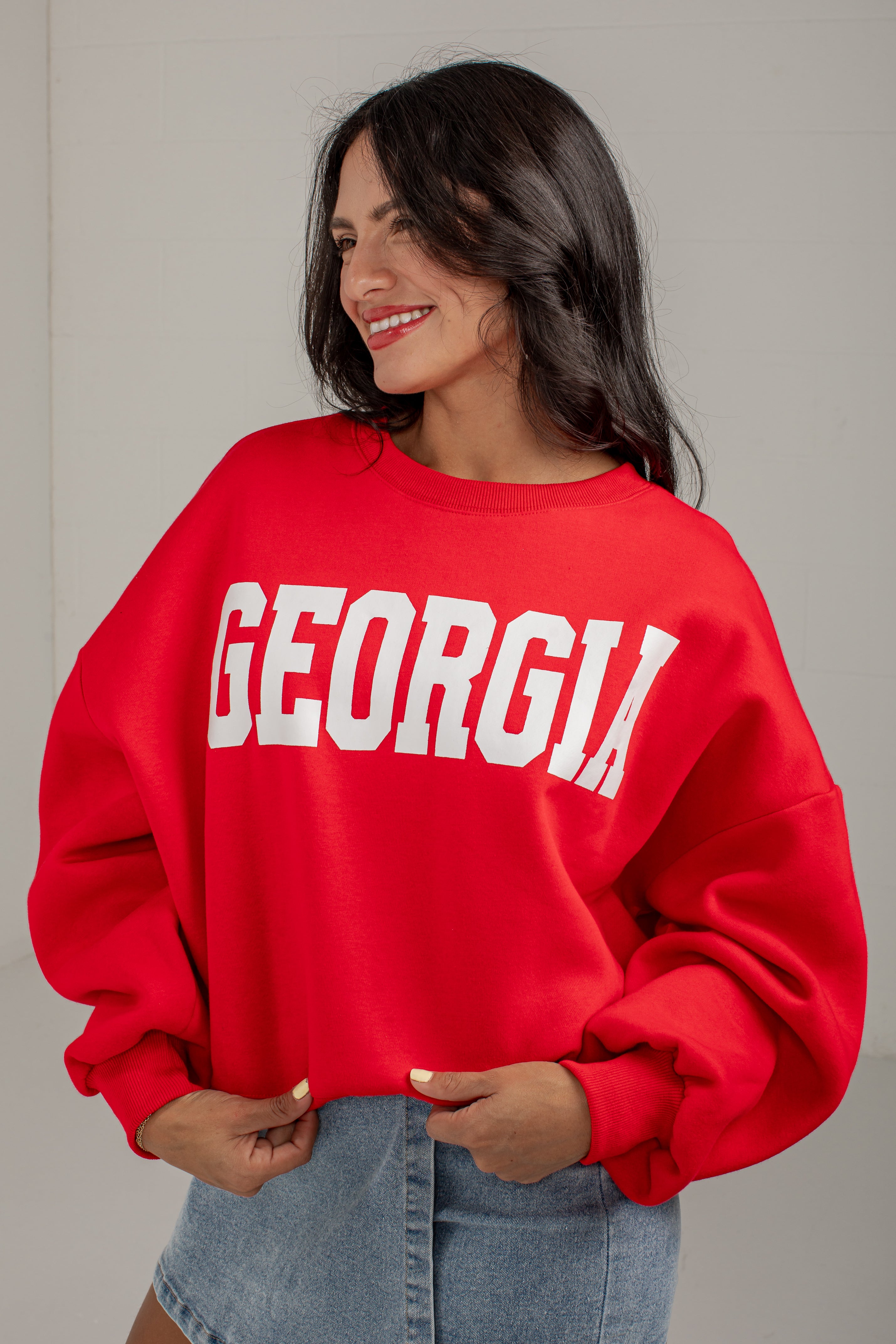 A woman wearing a bright red crewneck sweatshirt with &