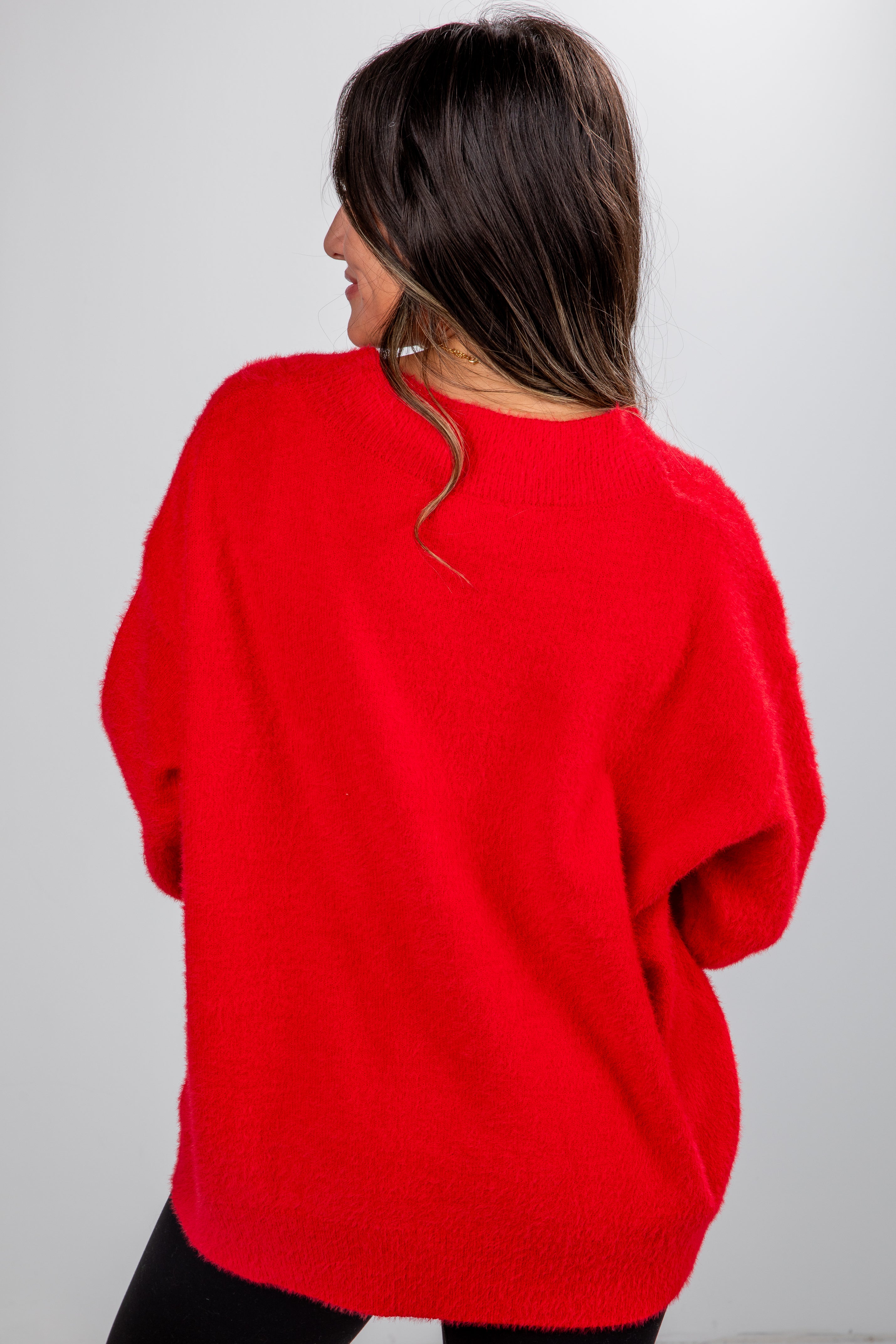 Person wearing a red sweater from behind on a plain background