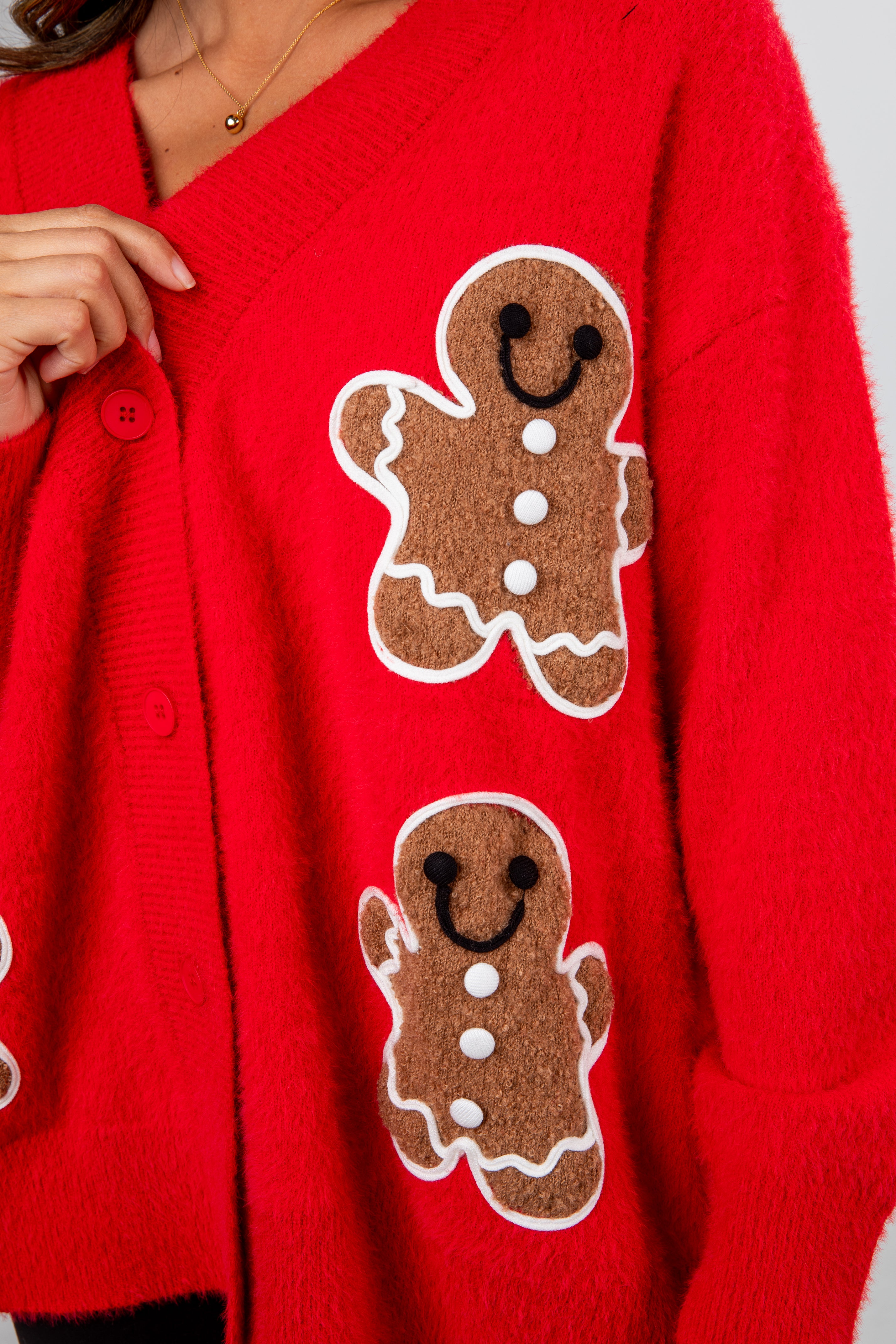 Red cardigan with gingerbread man patches on a plain background
