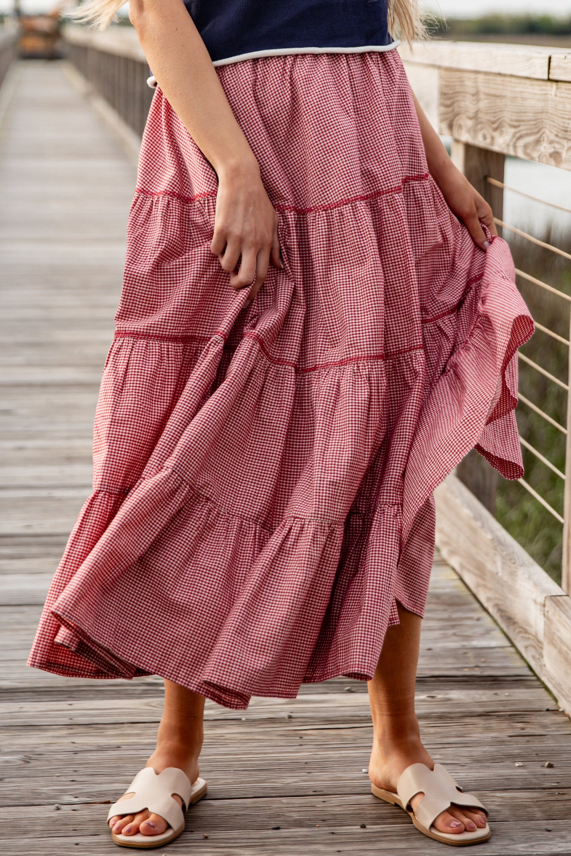 Person wearing a red checkered skirt on a wooden bridge