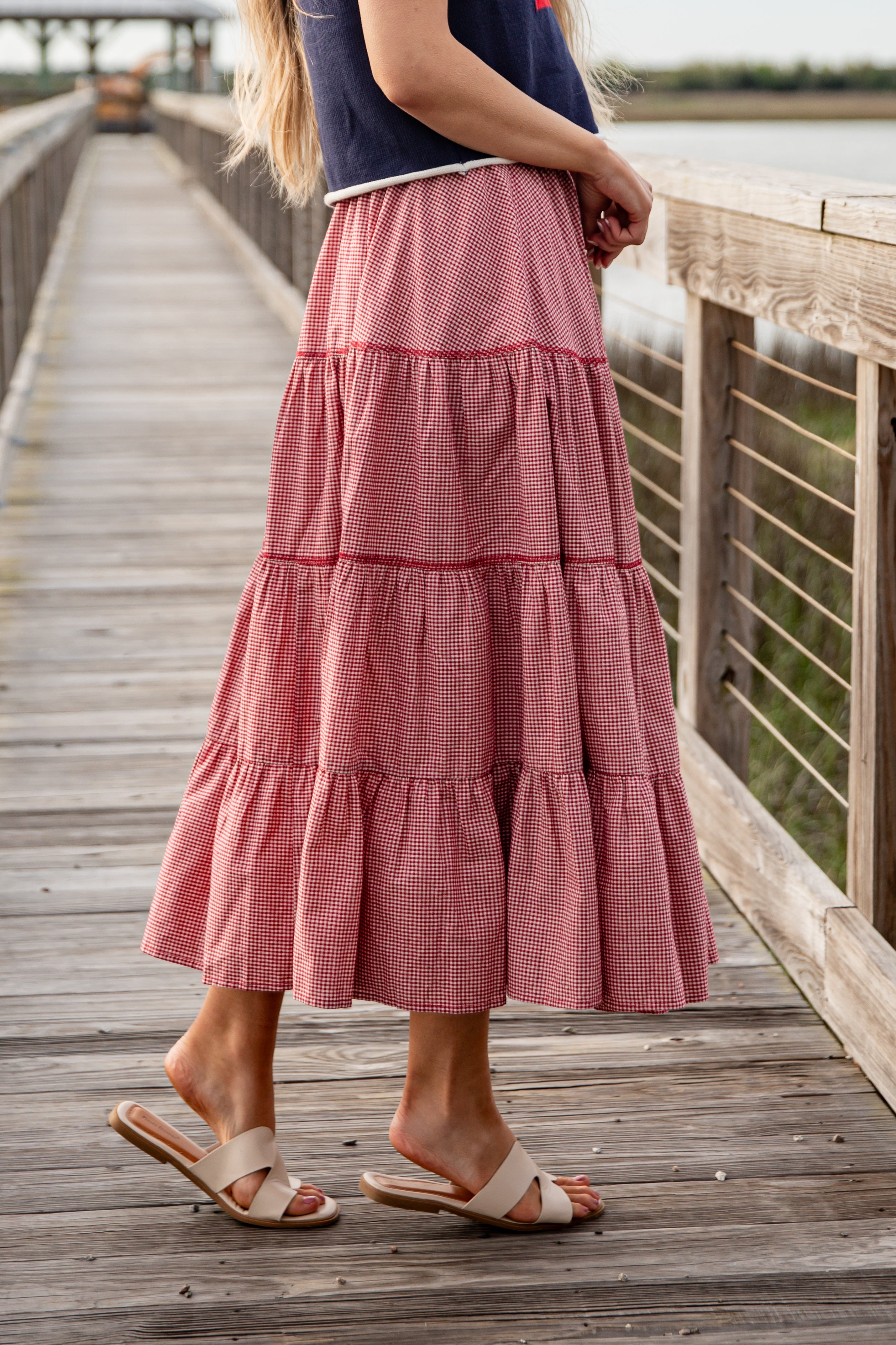 Person wearing a pink tiered skirt on a wooden dock.