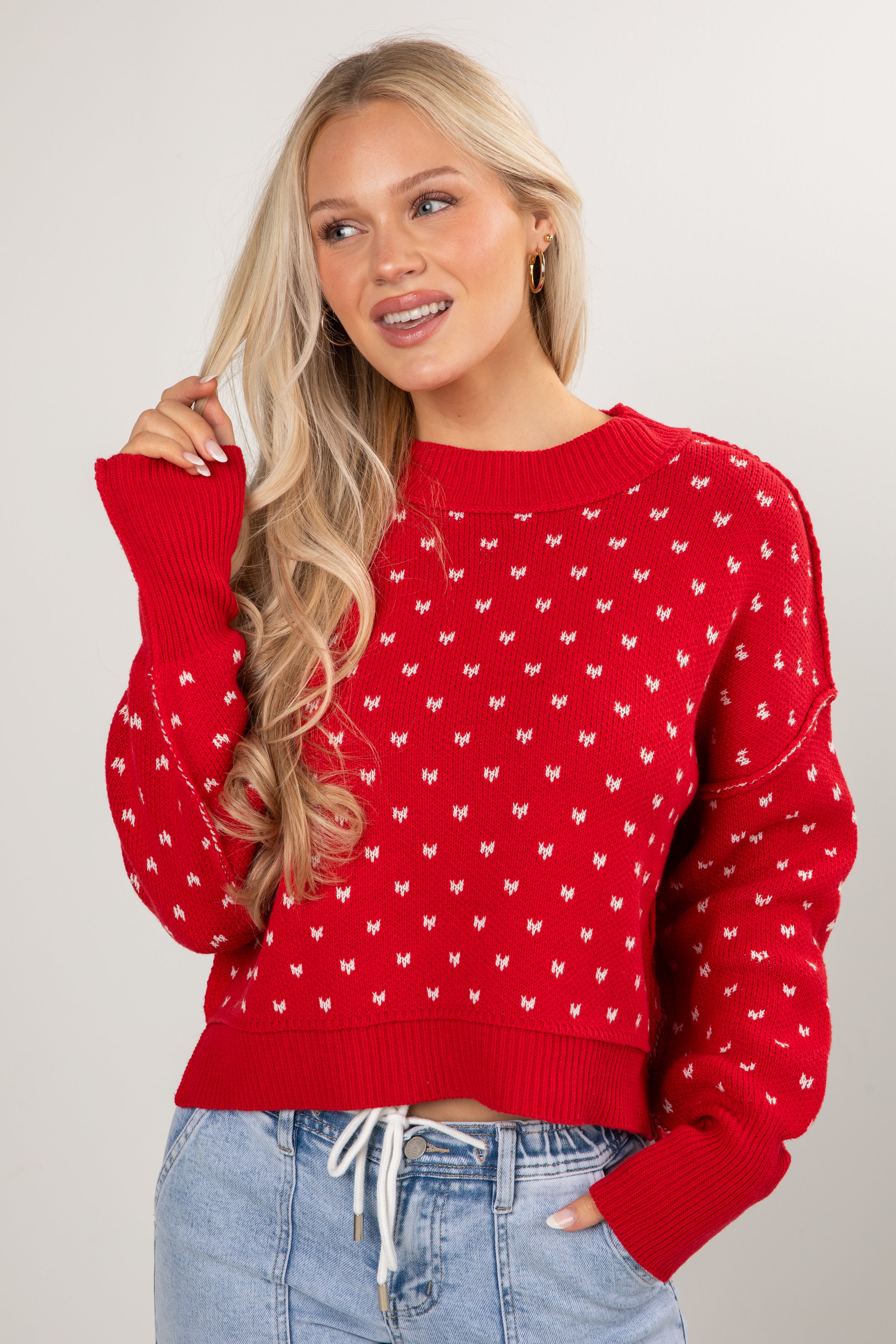 Woman wearing a red sweater with white patterns on a plain background