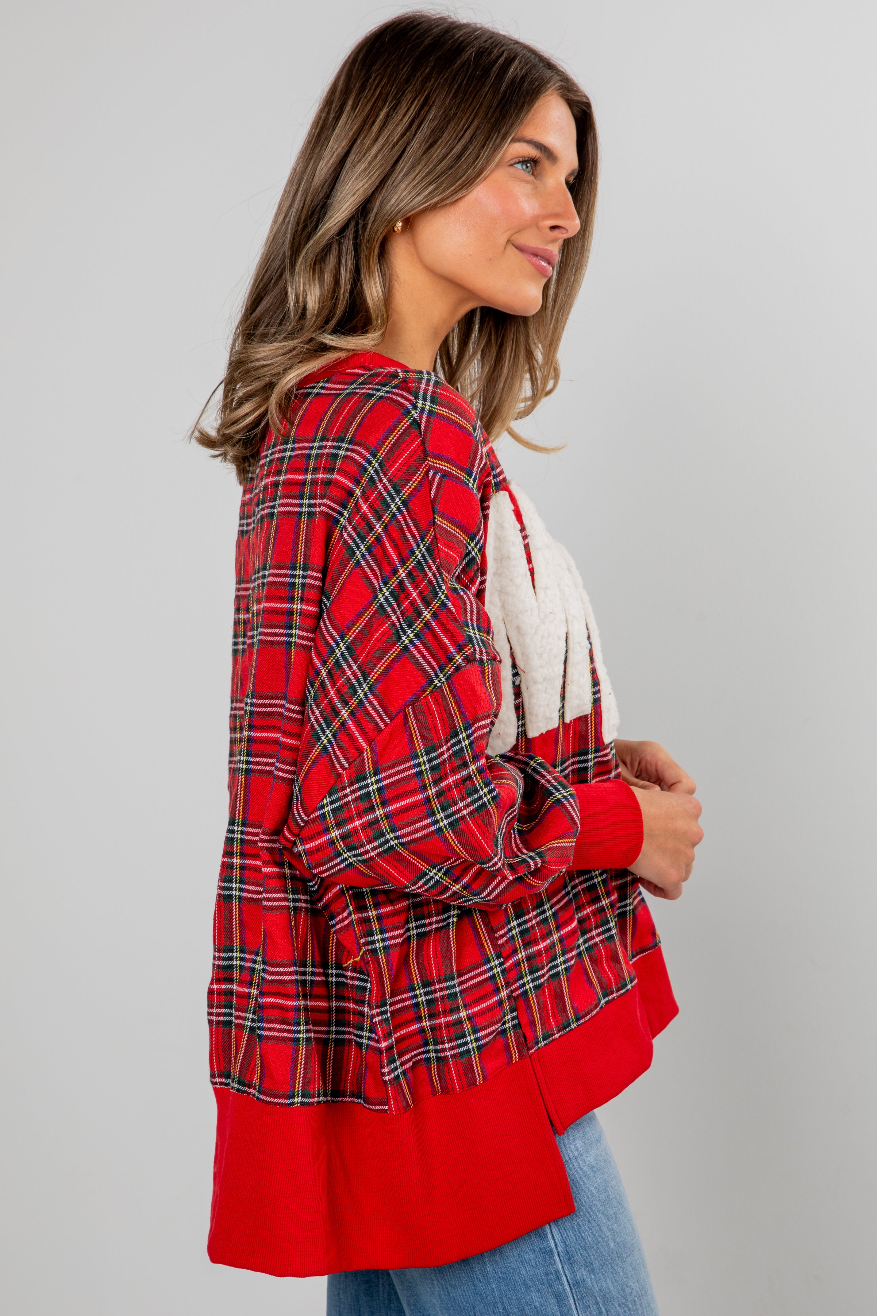 Woman wearing a red plaid jacket over a white top on a gray background