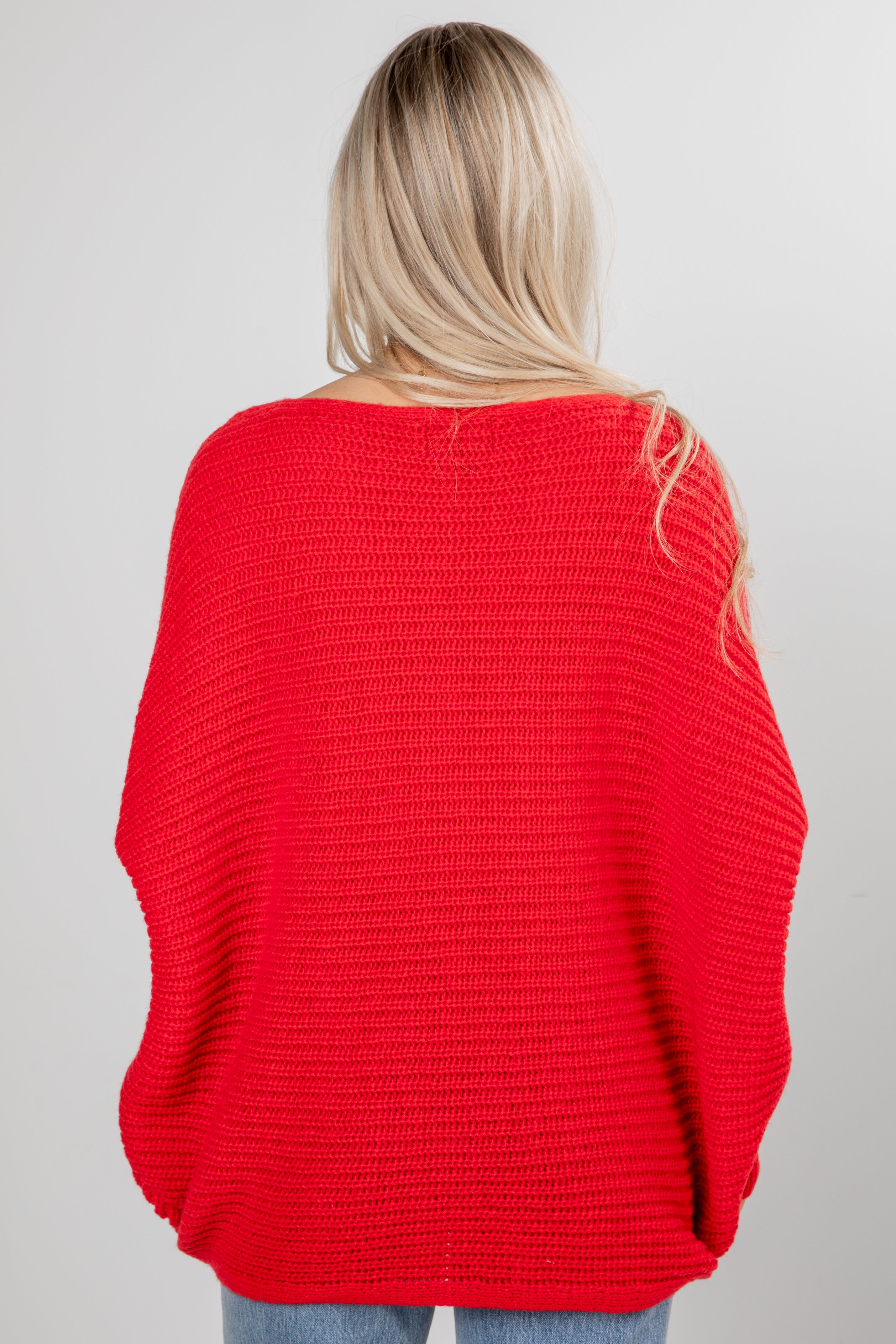 Person wearing a red sweater on a plain background