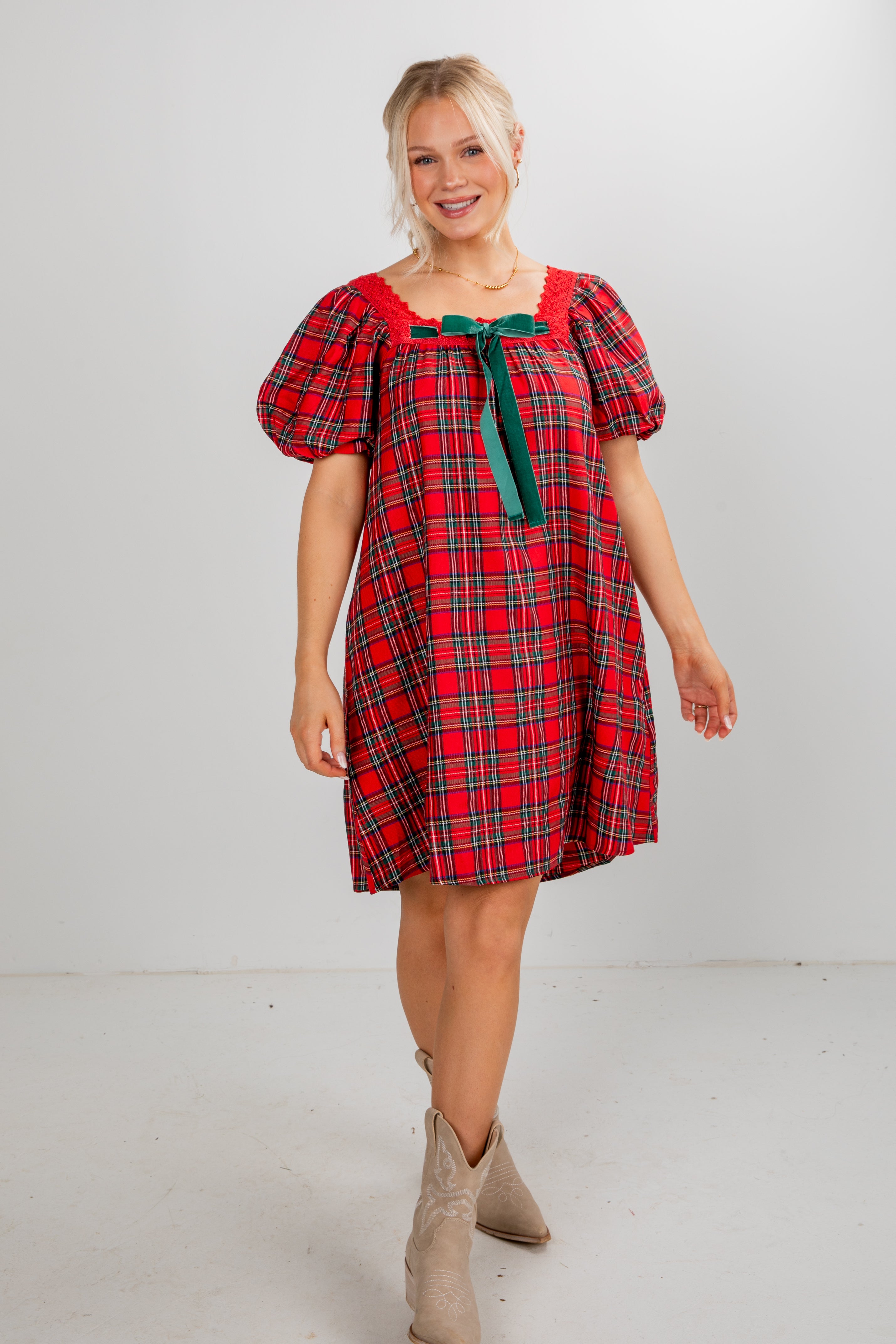 Woman wearing a red plaid dress with puff sleeves on a white background