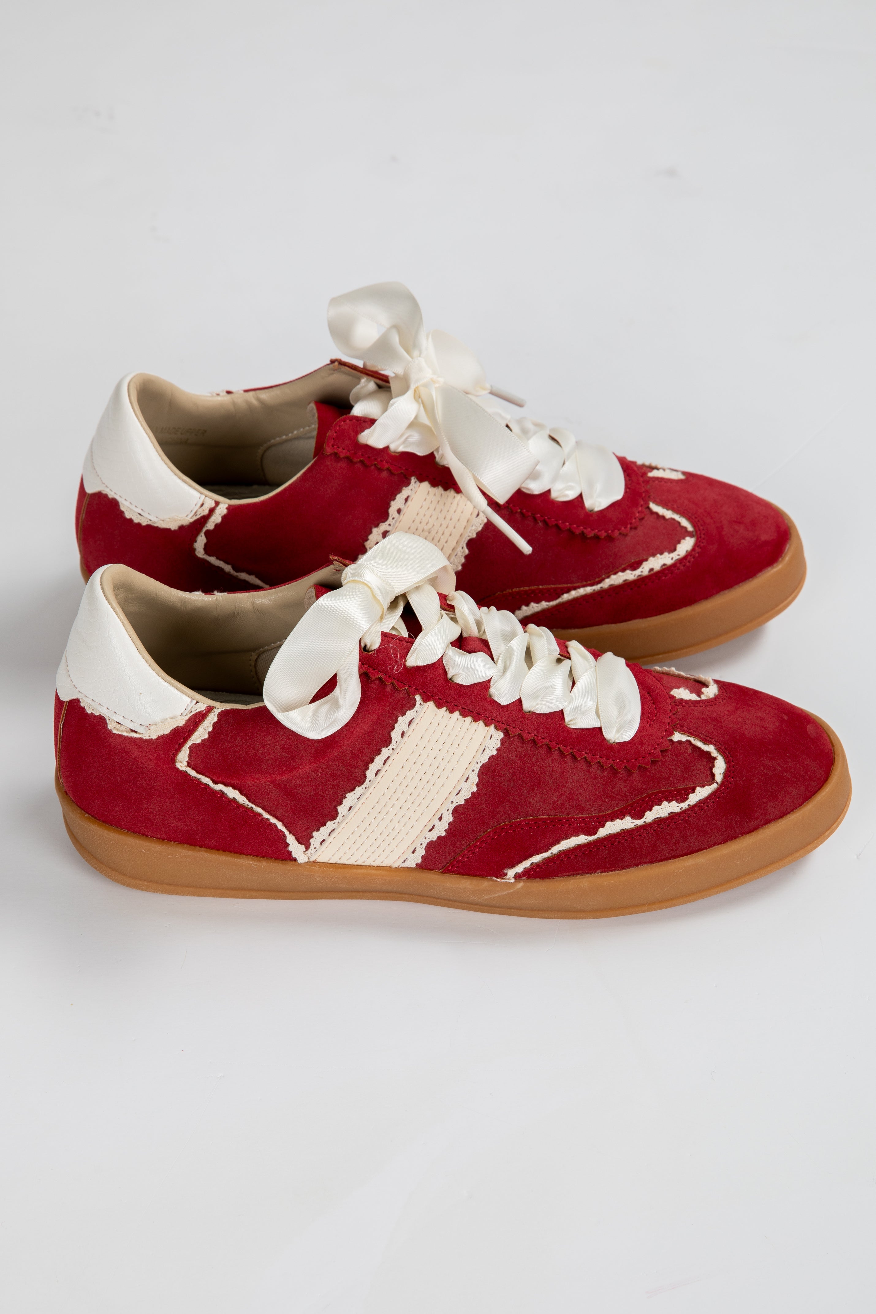 Red and white sneakers with brown soles on a light gray background