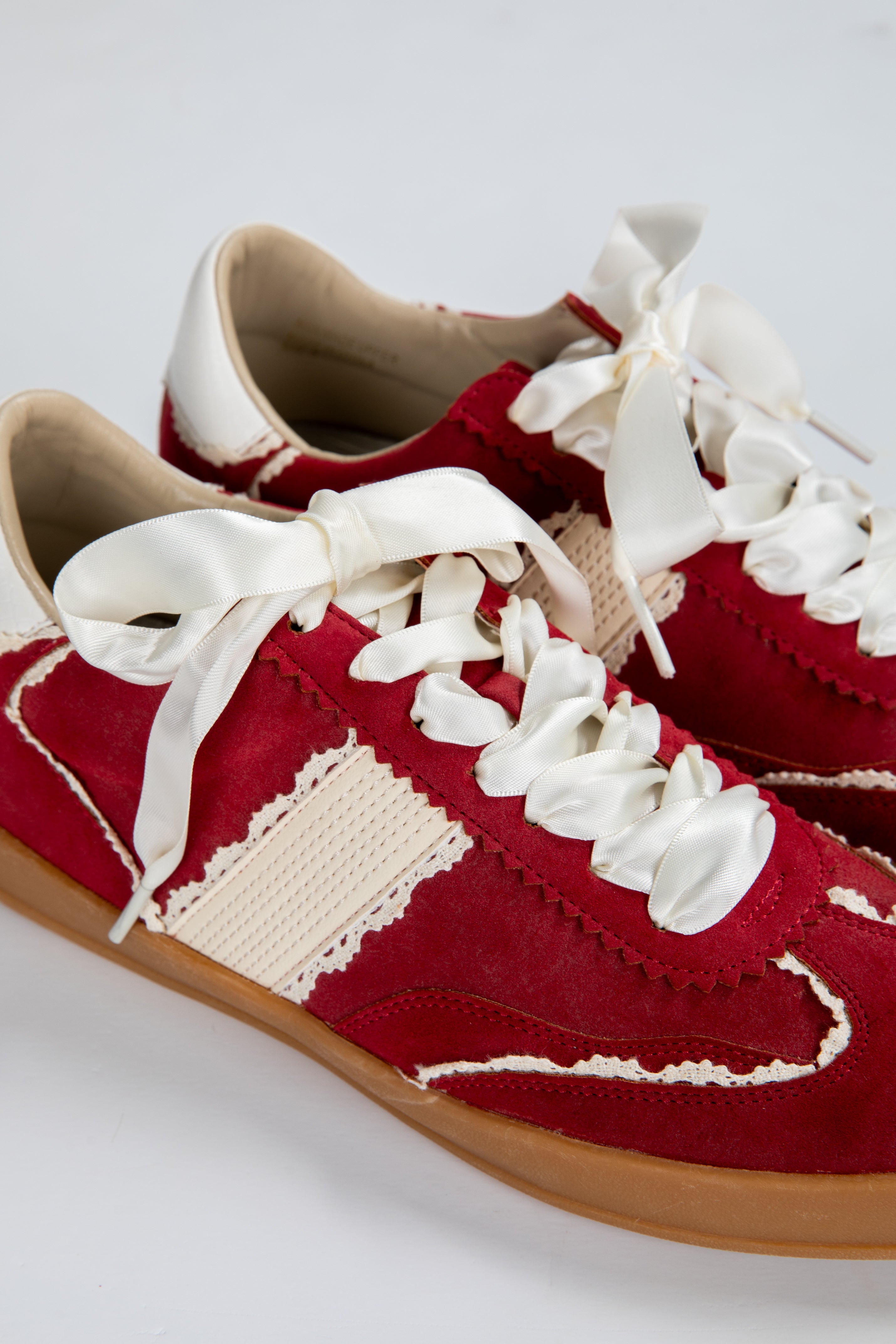 Red sneakers with white laces on a light gray background