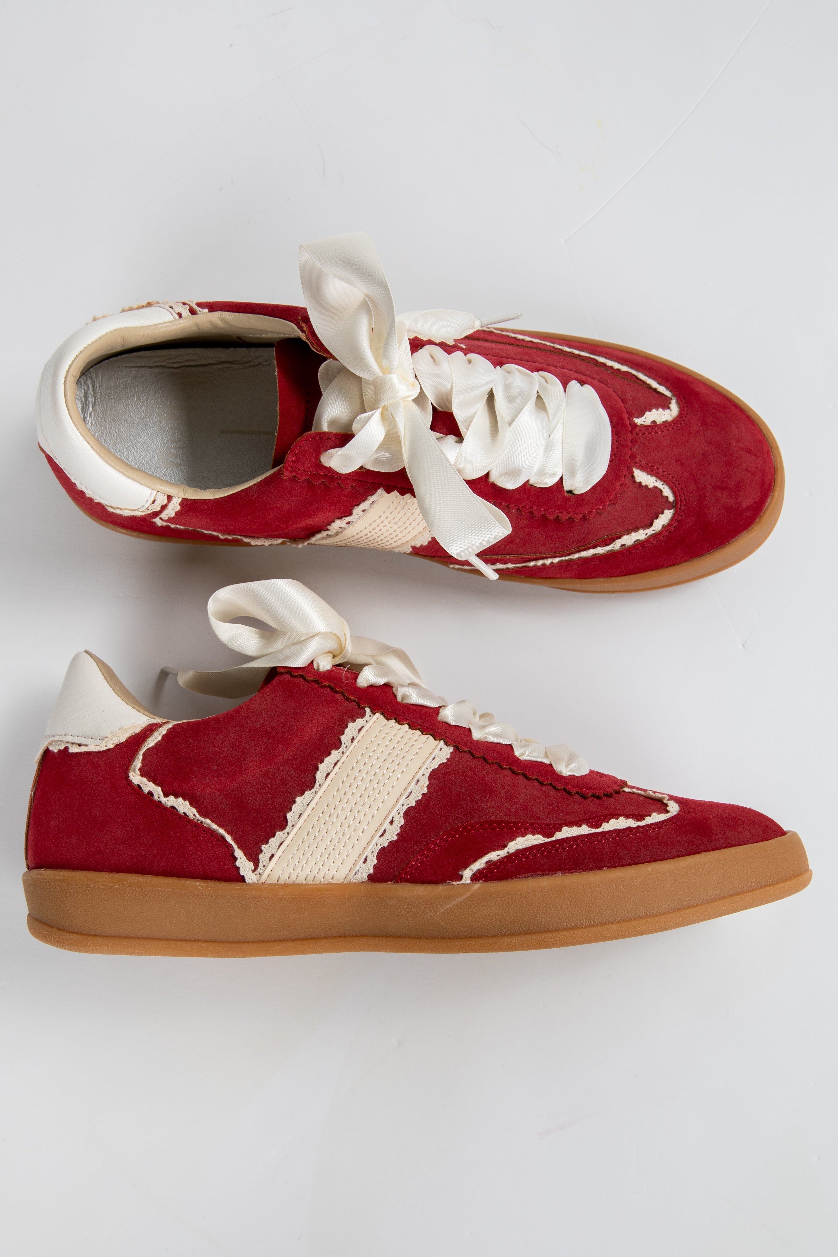 Red sneakers with white laces and soles on a light gray background