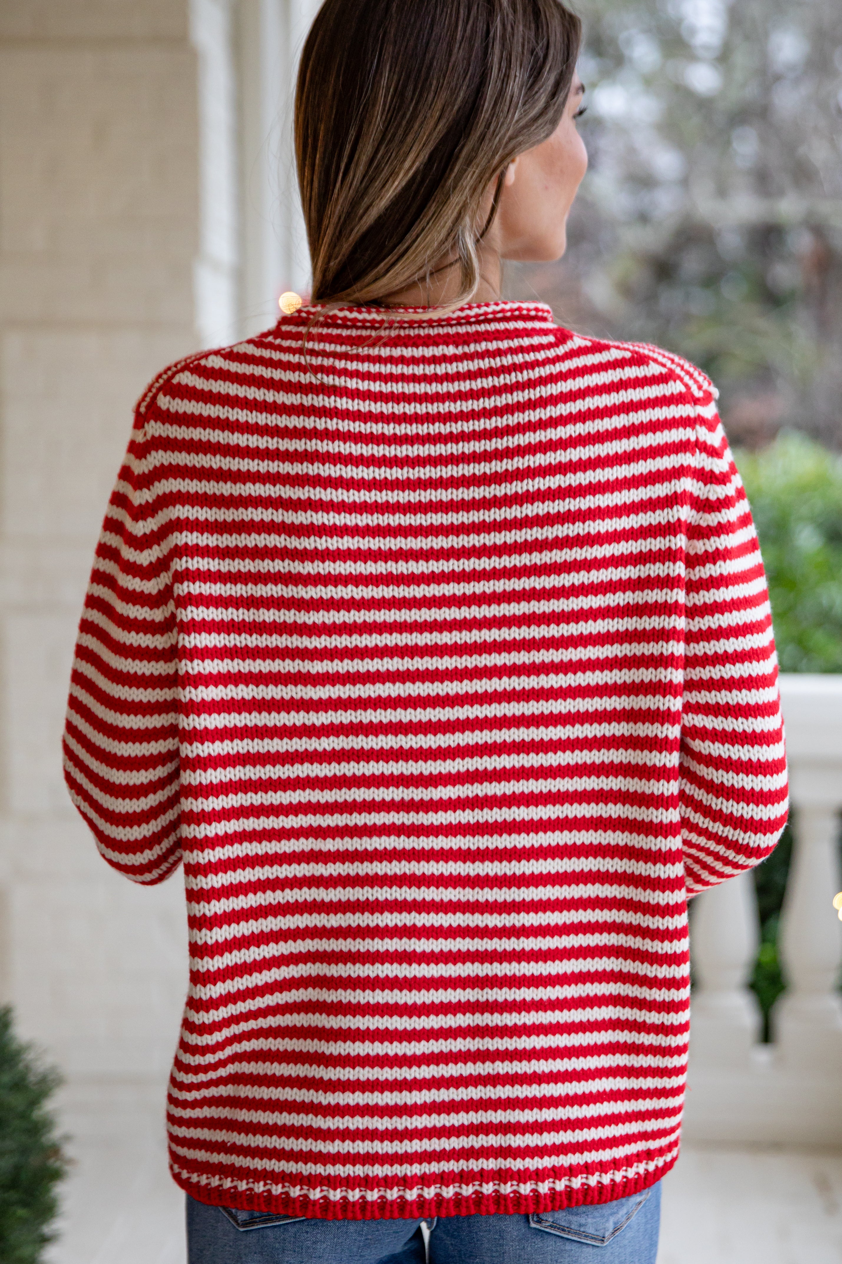 Person wearing a red and white striped sweater outdoors.