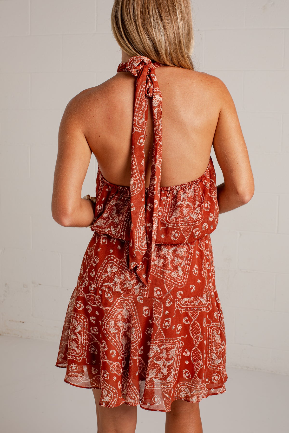 rust mini dress features an ivory paisley print, a flattering halter neckline, and a flowy silhouette