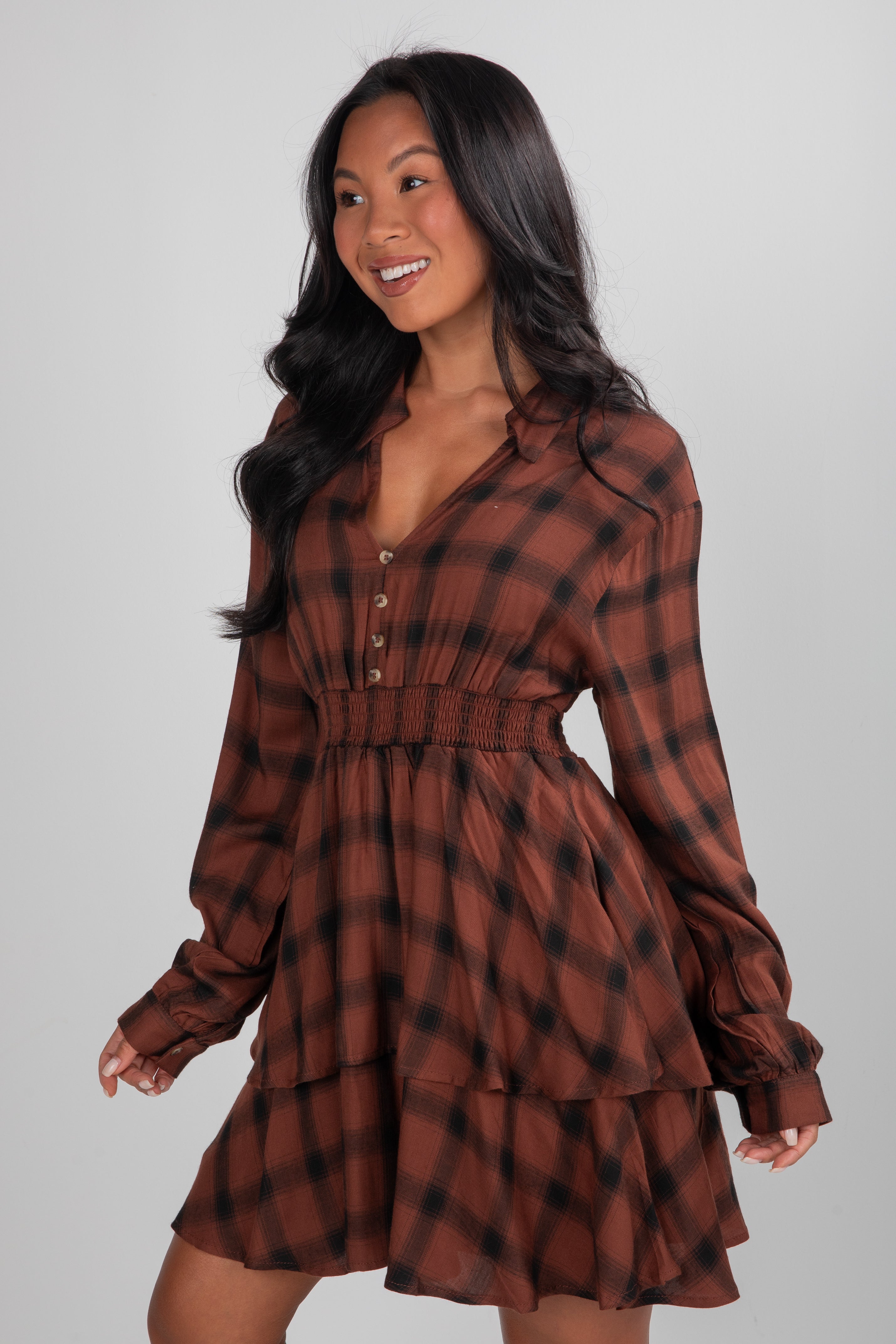 Woman wearing a brown plaid dress against a gray background