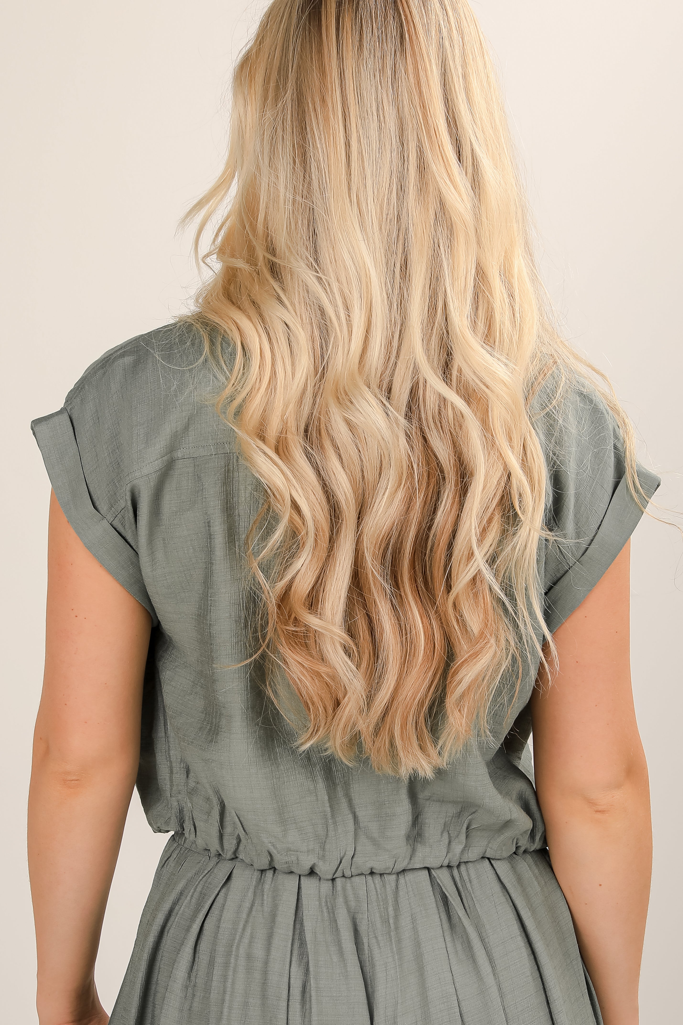 Woman wearing a green dress with long blonde hair on a beige background