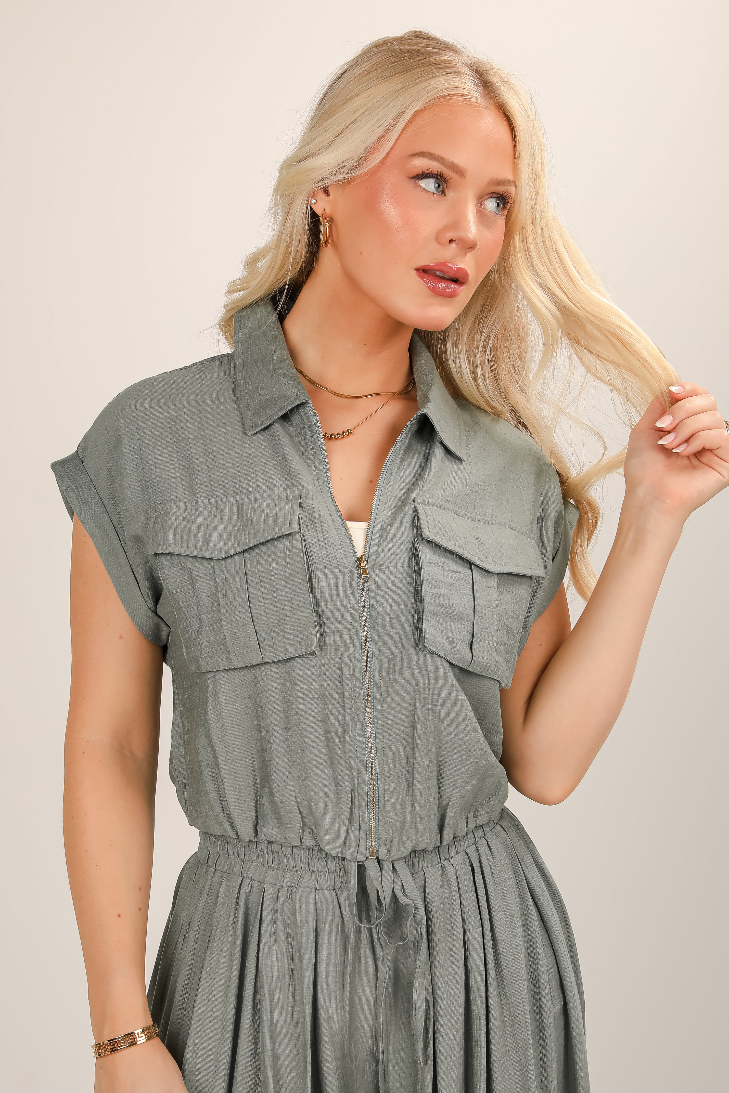 Woman wearing a gray sleeveless dress against a plain background