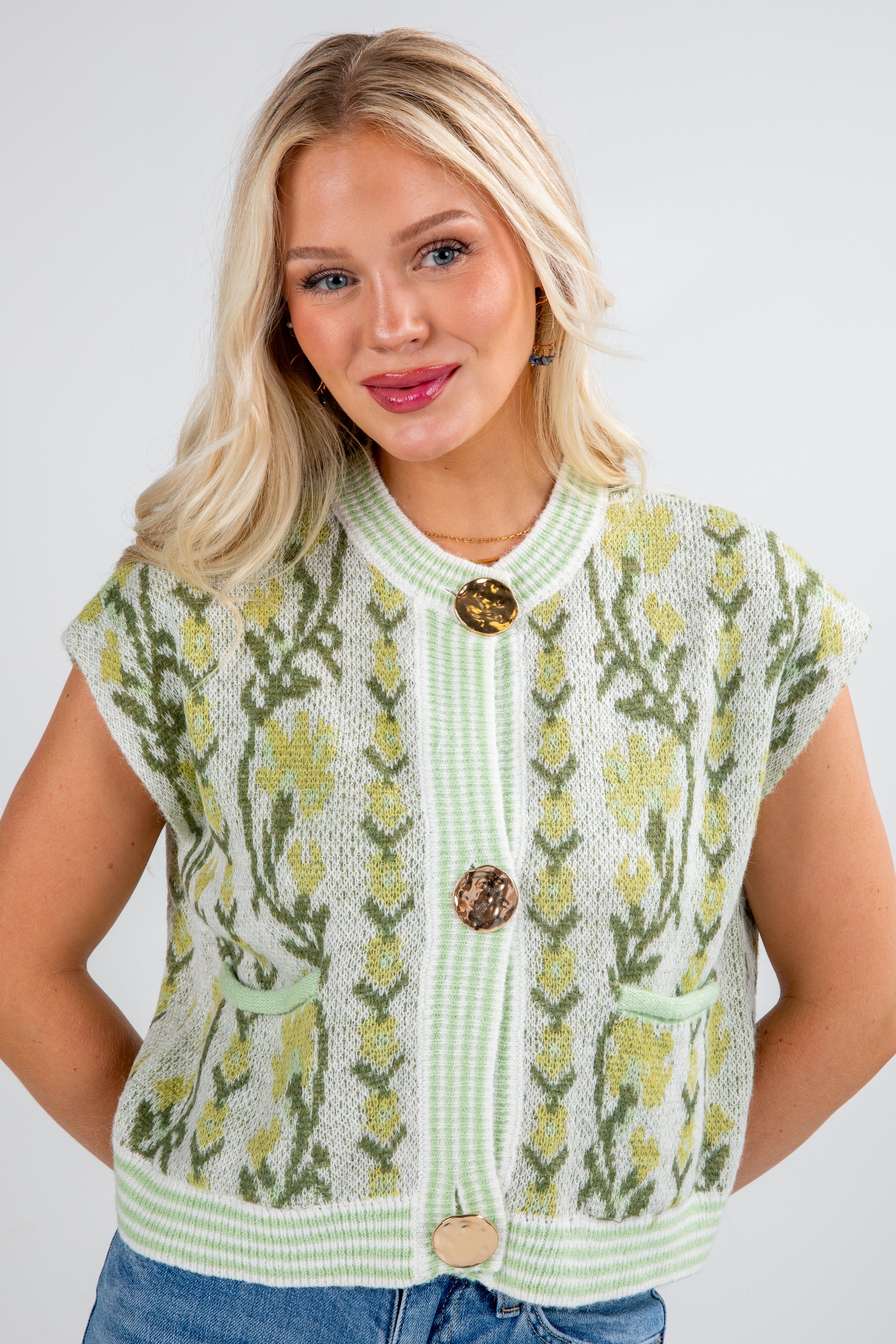 Woman wearing a green knitted cardigan with floral patterns on a white background