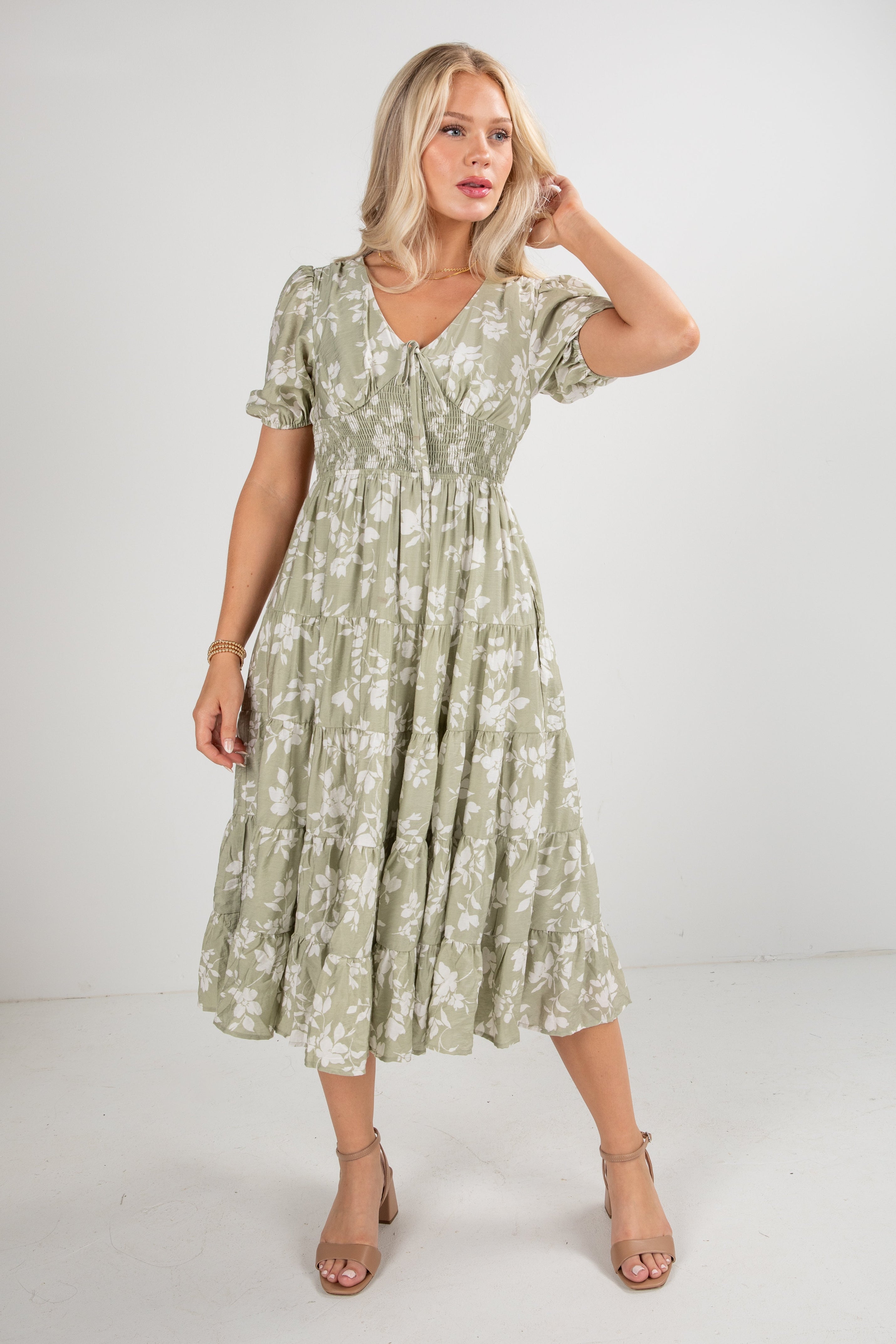 Woman wearing a green floral dress against a white background