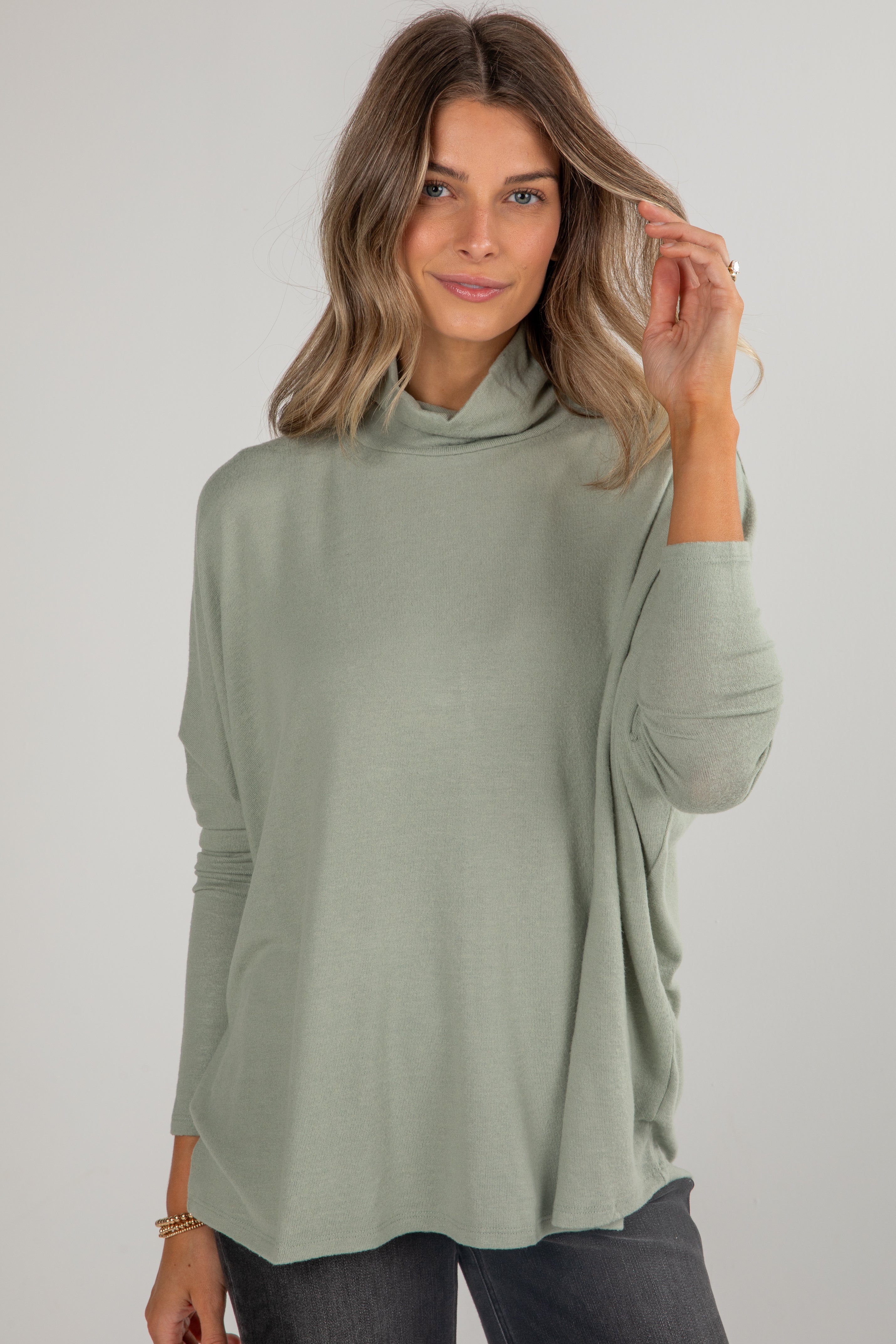 Woman wearing a green long-sleeve top against a plain background