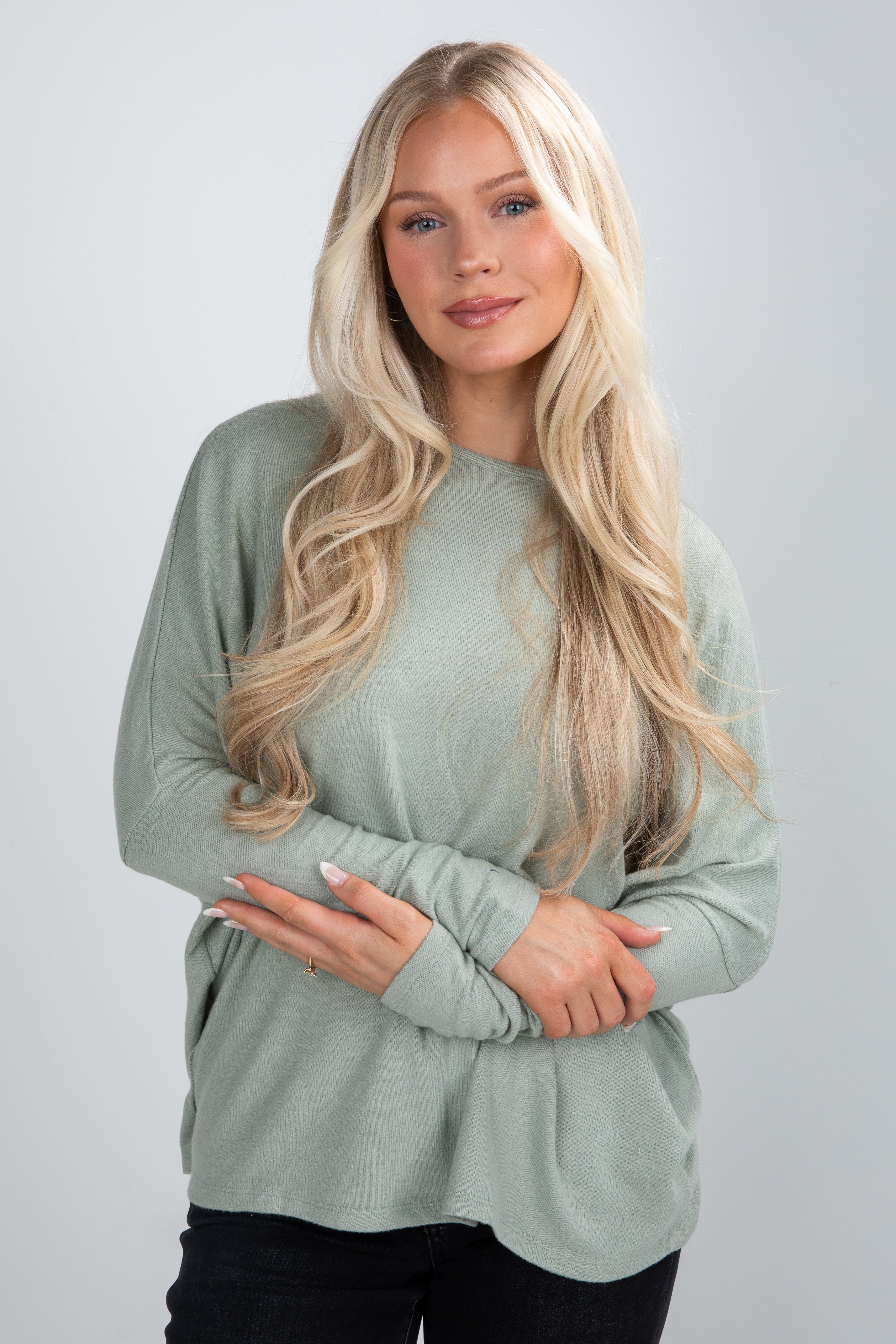 Woman wearing a light green long-sleeve top against a plain background