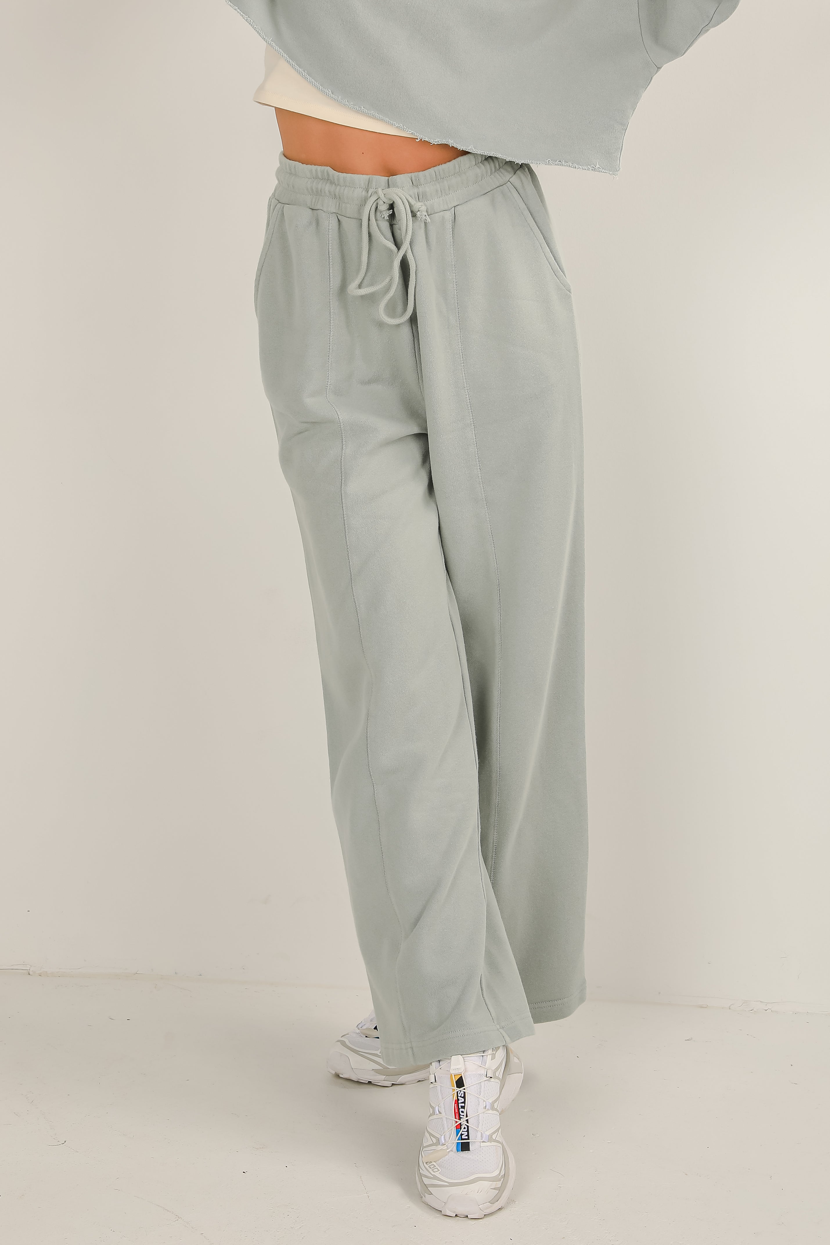 Light gray sweatpants worn by a person on a white background