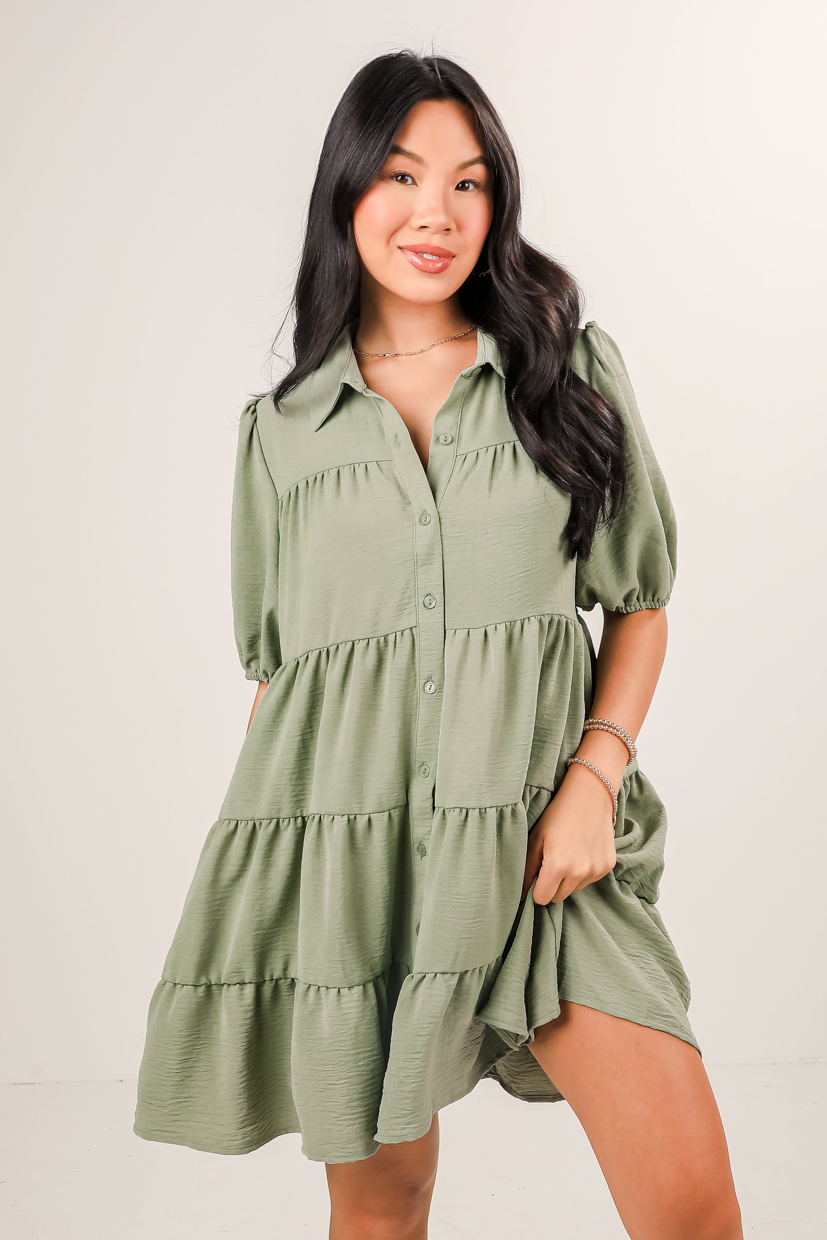 Woman wearing a green tiered dress against a plain background