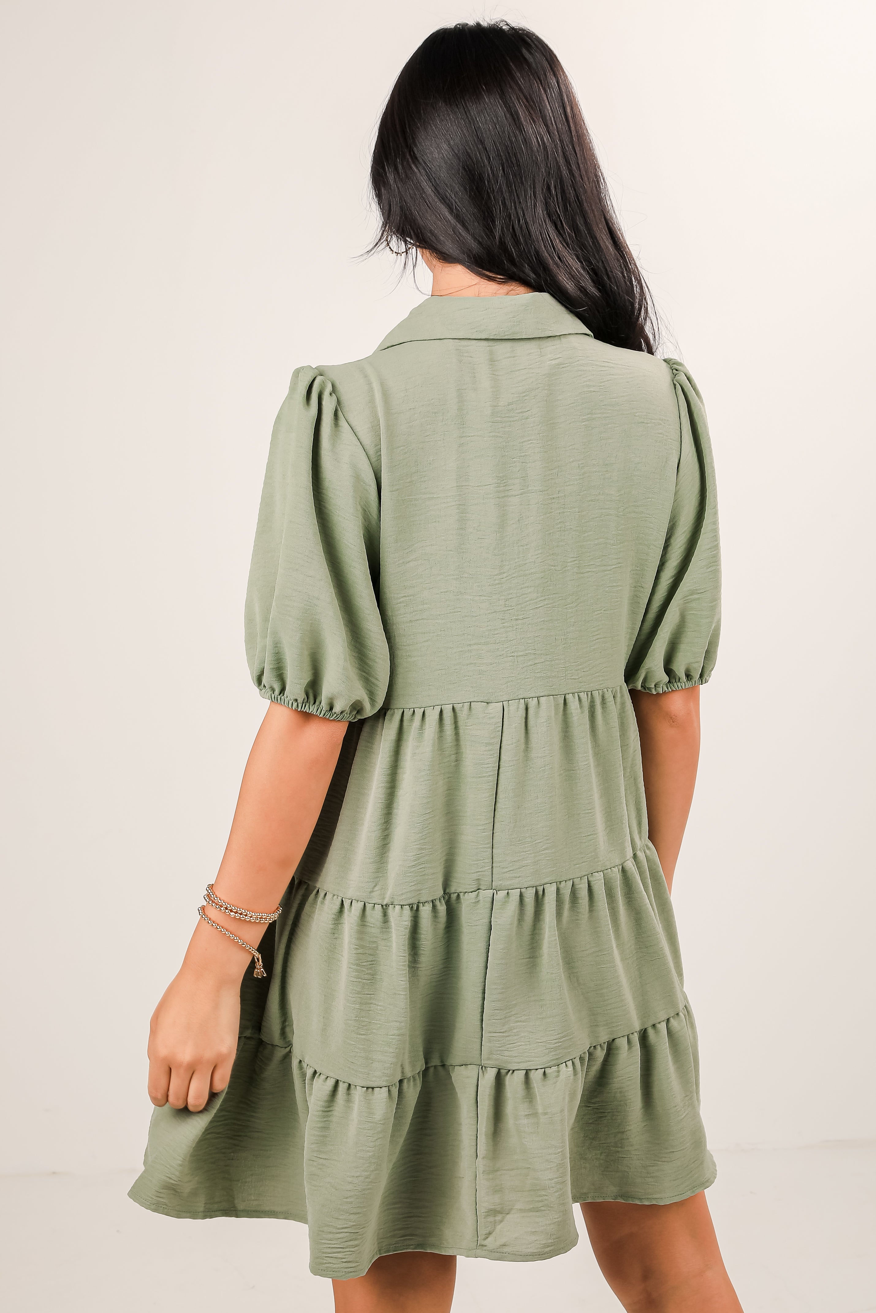 Woman wearing a green dress with puff sleeves against a white background