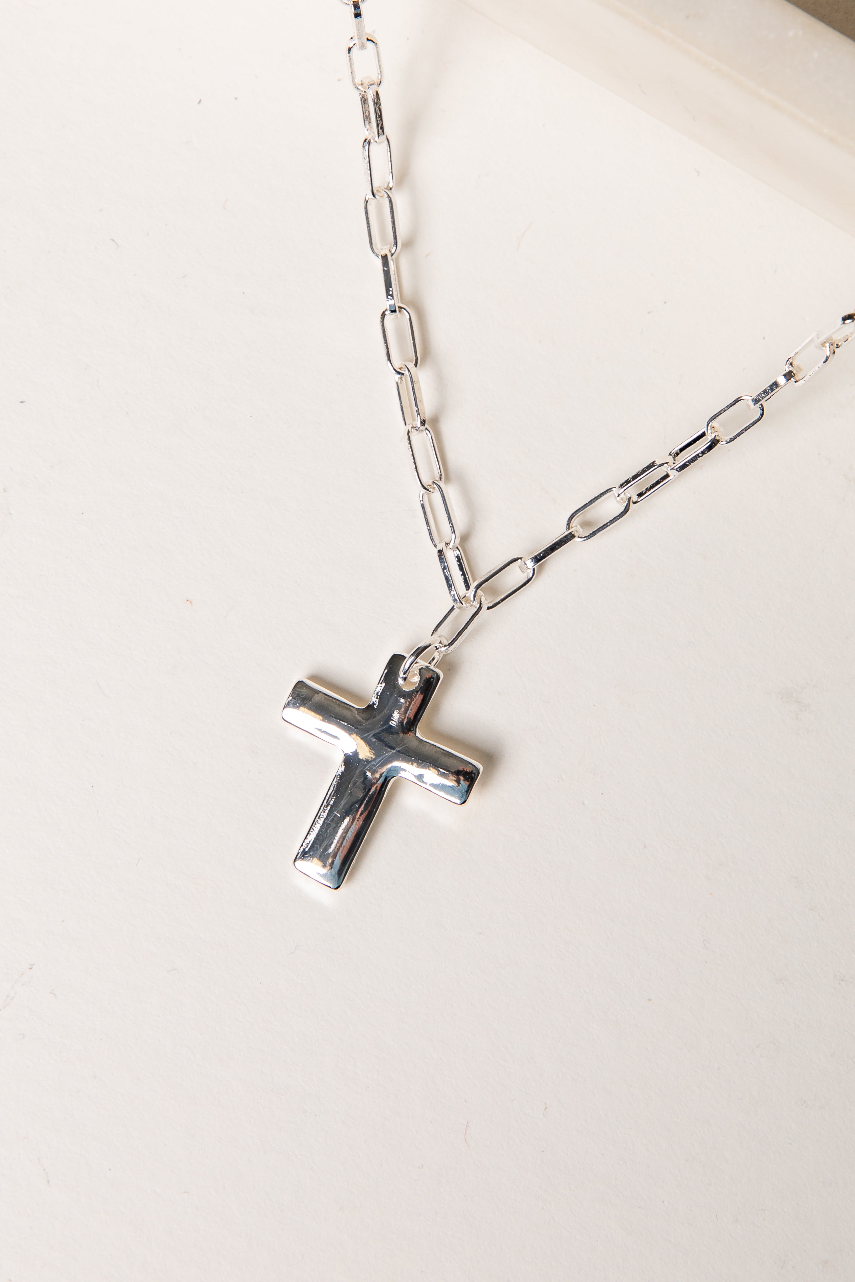 Silver cross necklace on a white background