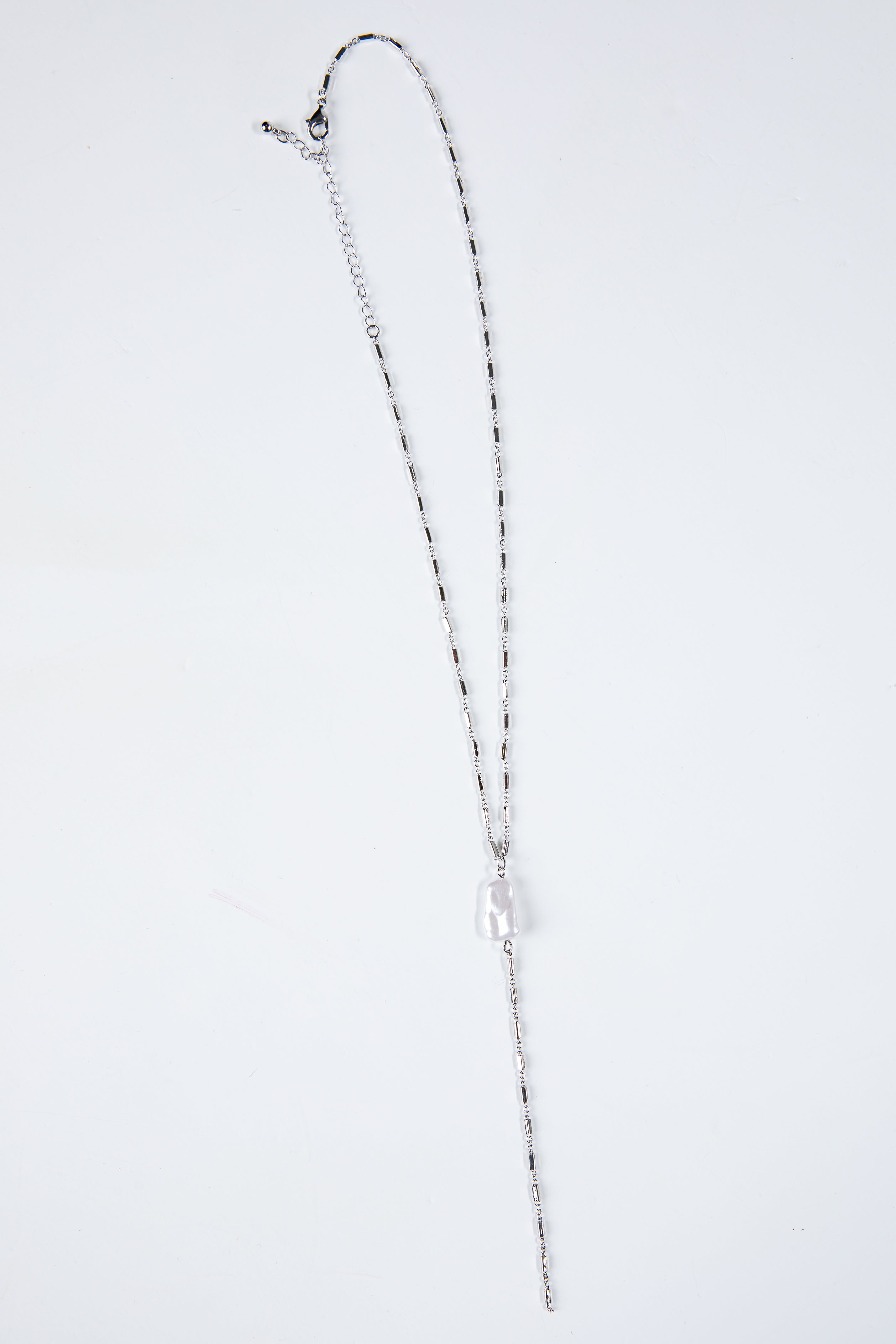 Silver necklace on a light gray background