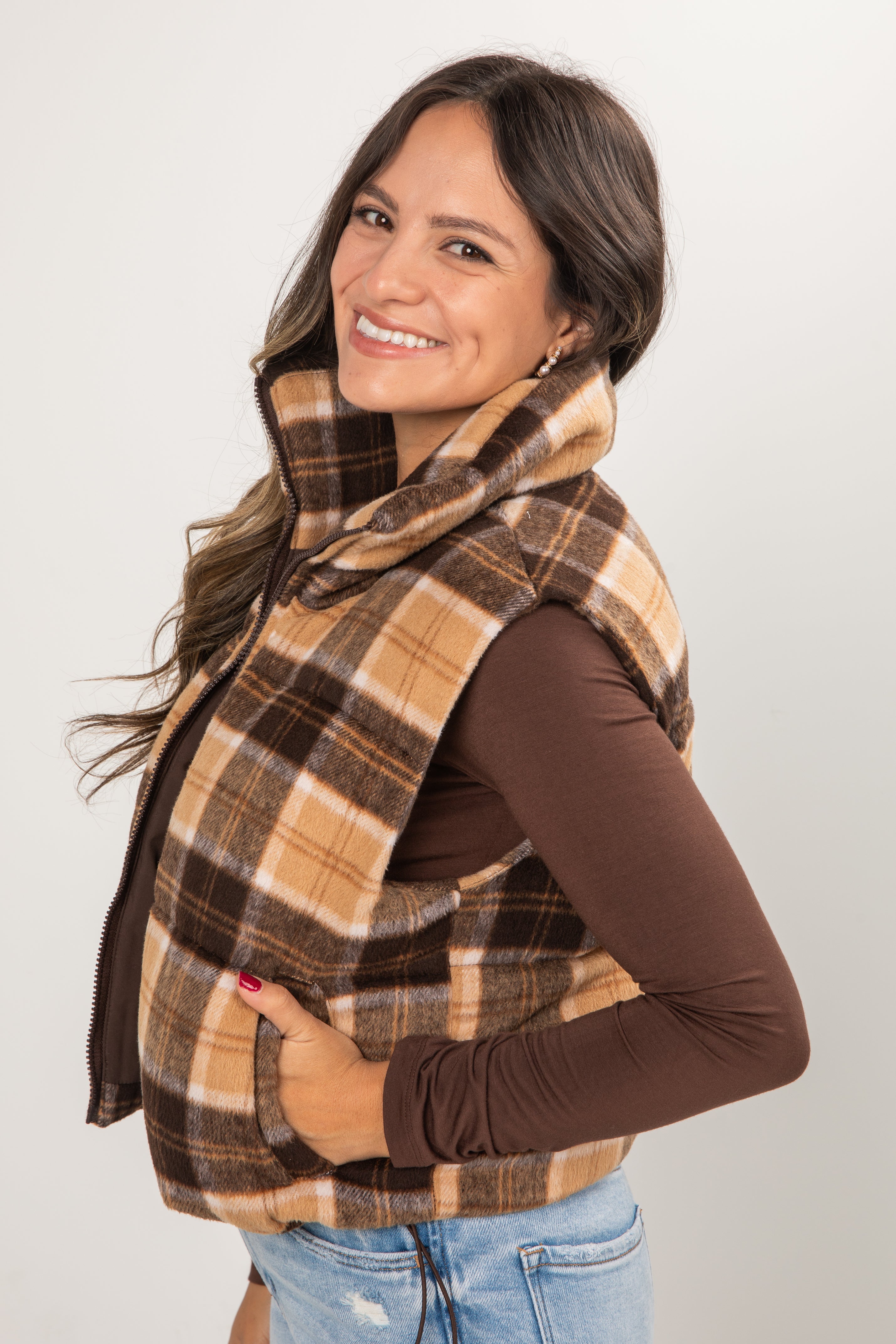 Woman wearing a plaid scarf and vest on a plain background