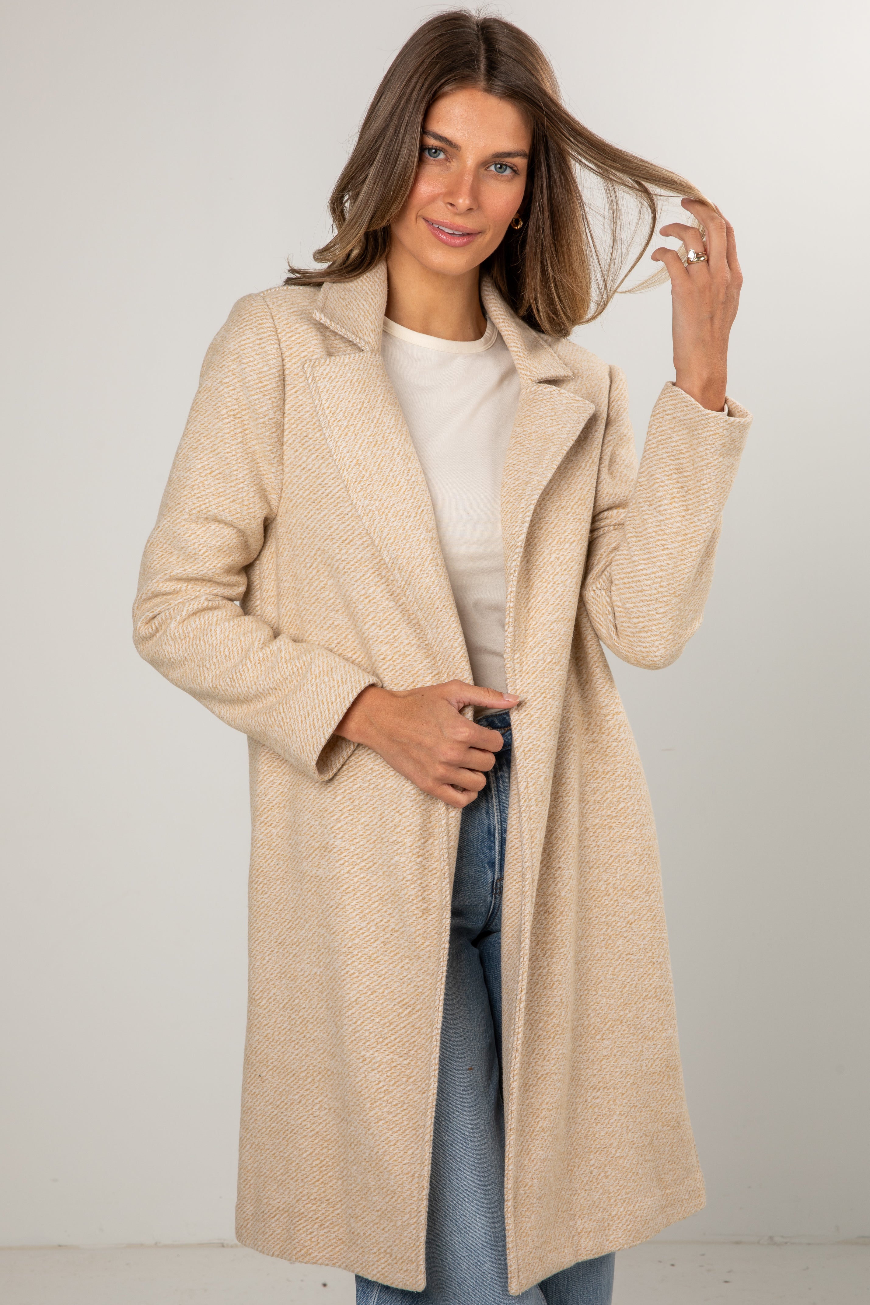 Woman wearing a beige coat with a plain background