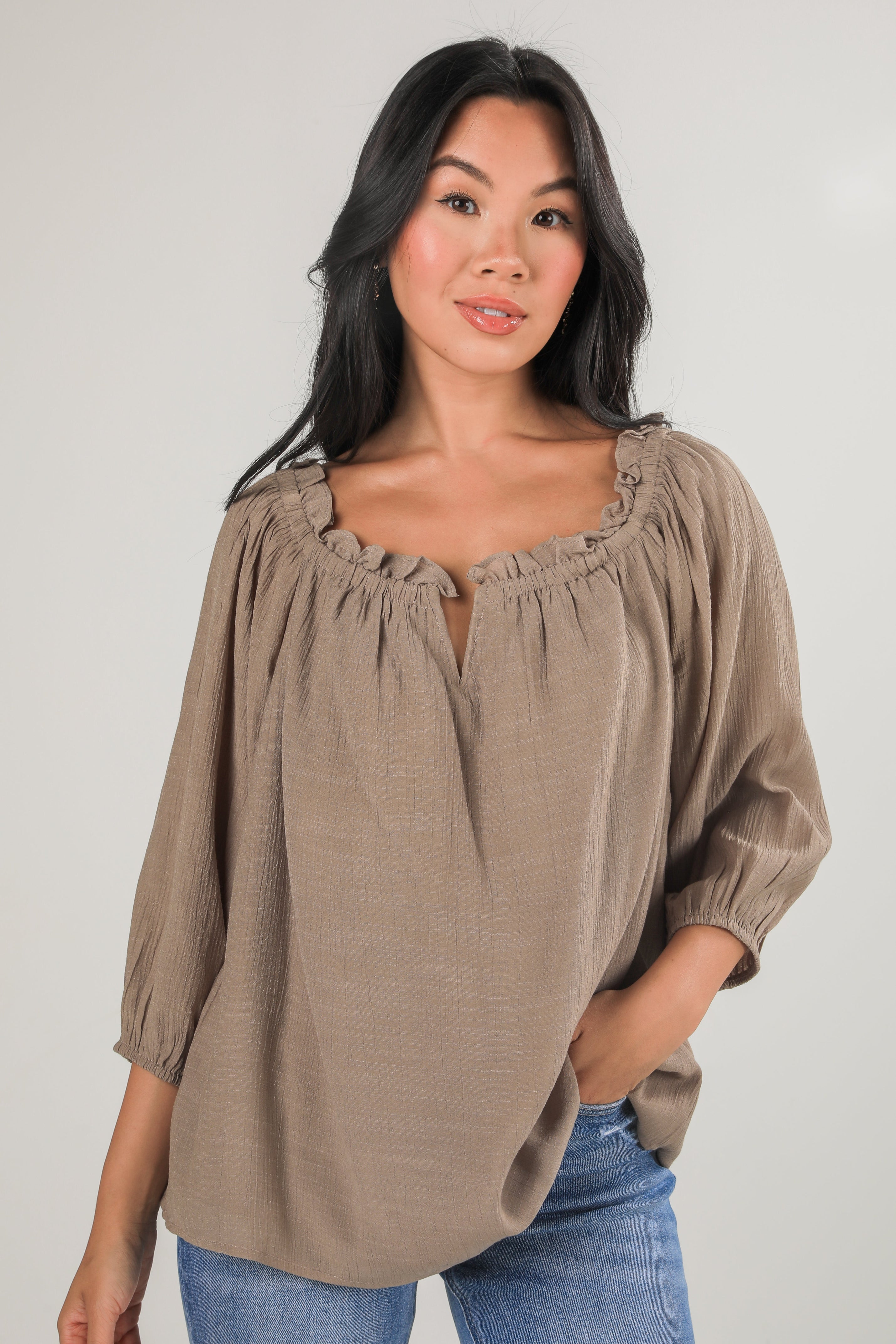 Woman wearing a brown blouse with a plain background