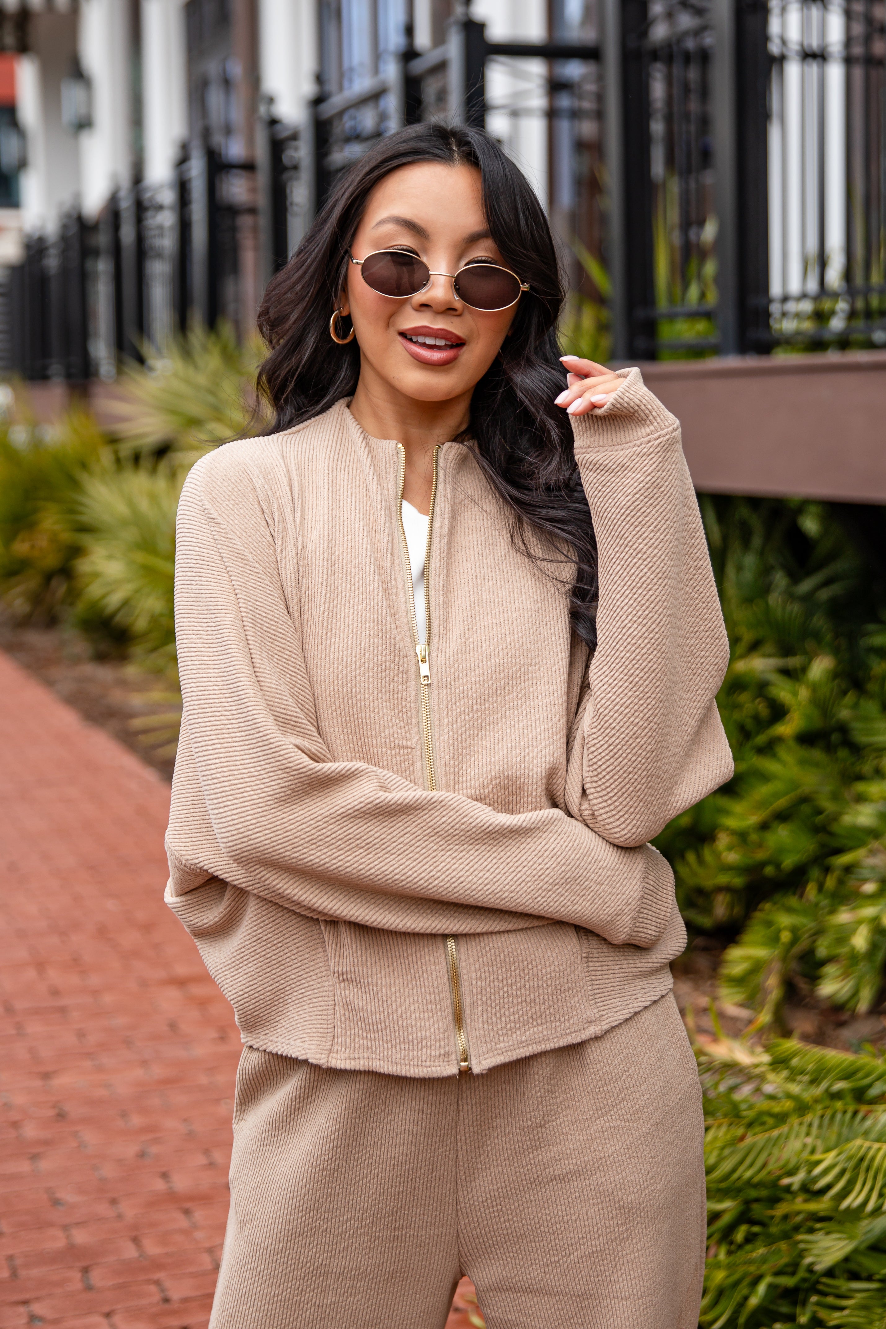 Woman wearing a beige outfit with sunglasses in an outdoor setting
