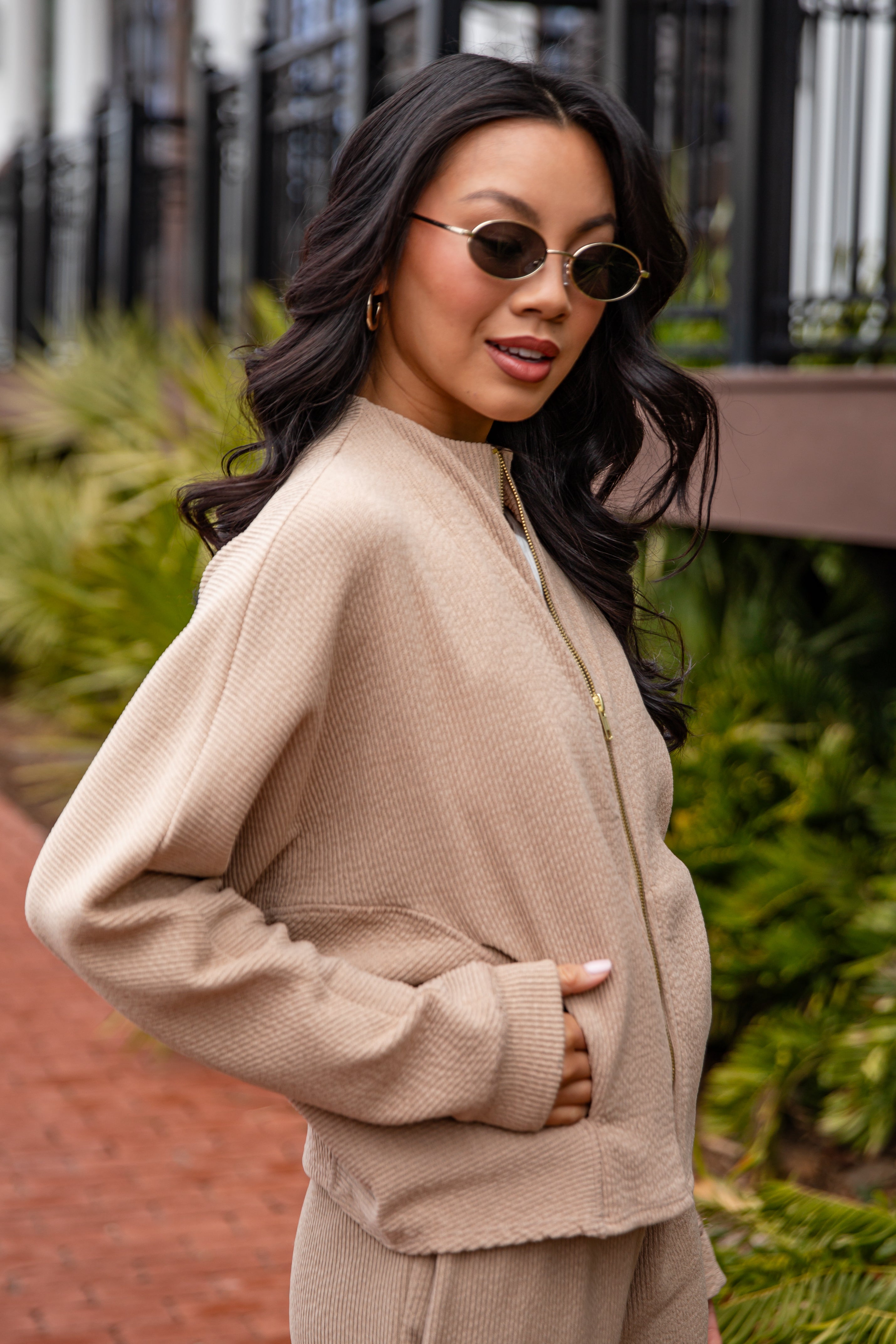 Woman wearing a beige sweater and sunglasses outdoors