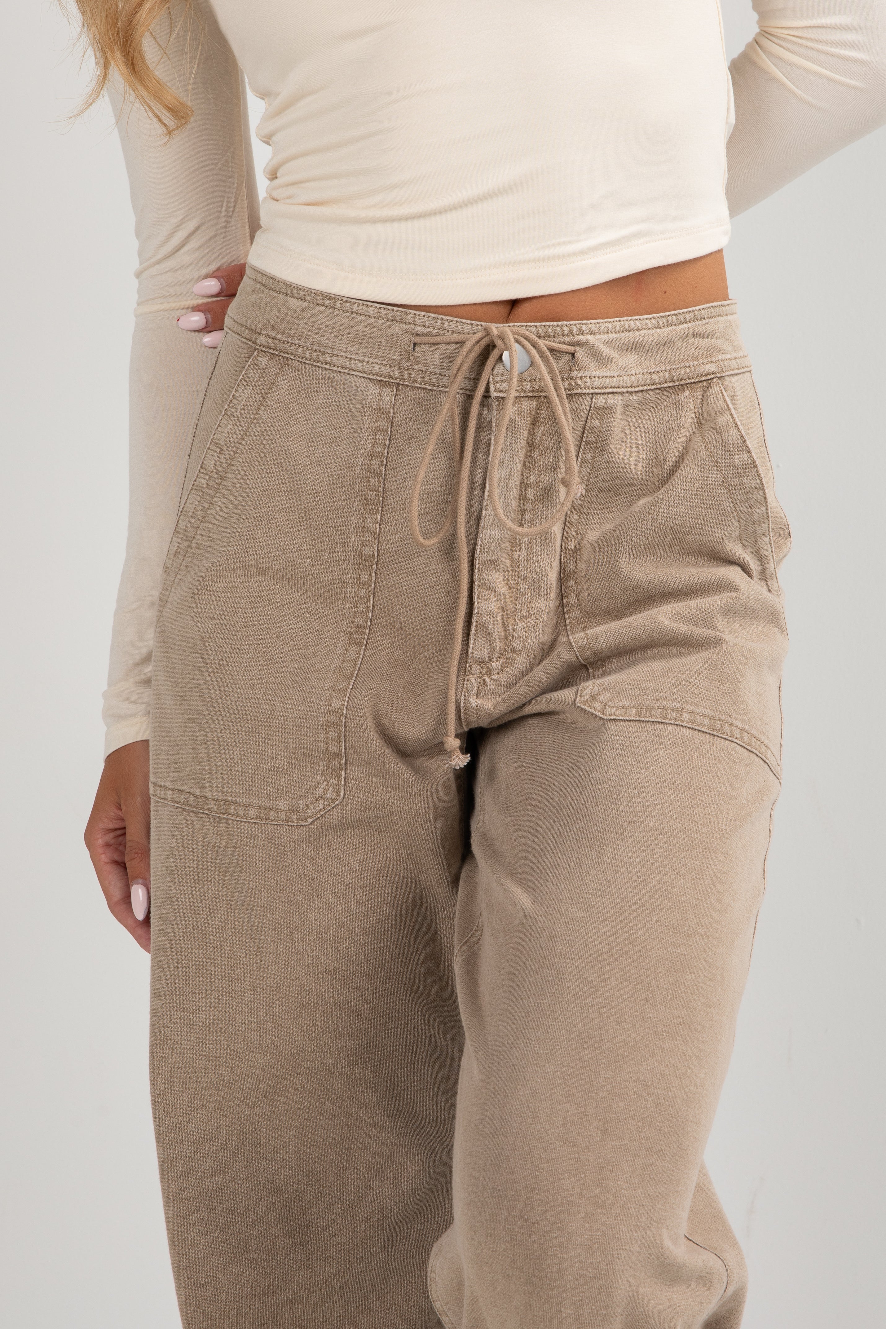 Beige pants worn by a person on a white background