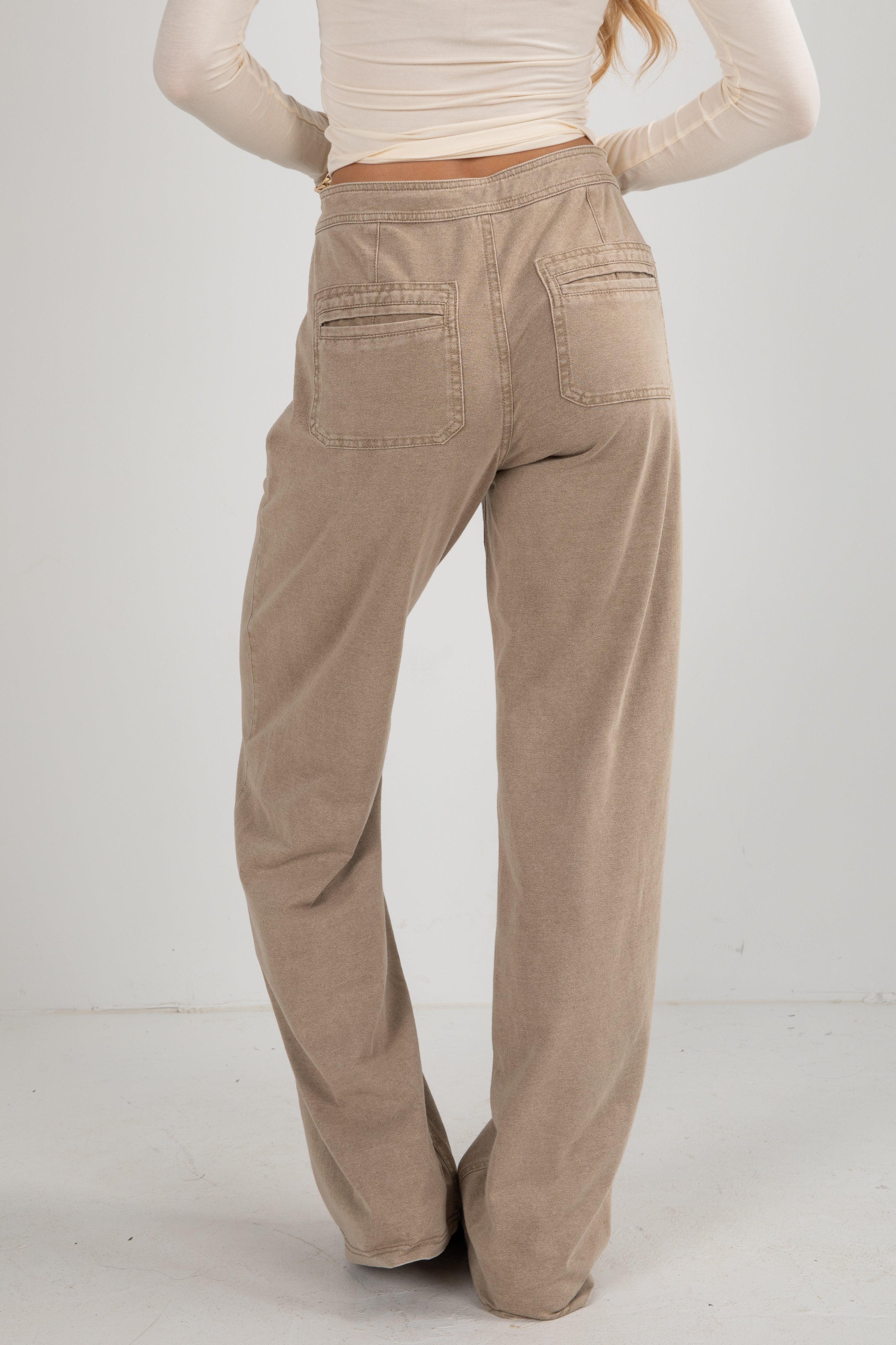 Beige corduroy pants worn by a person on a white background