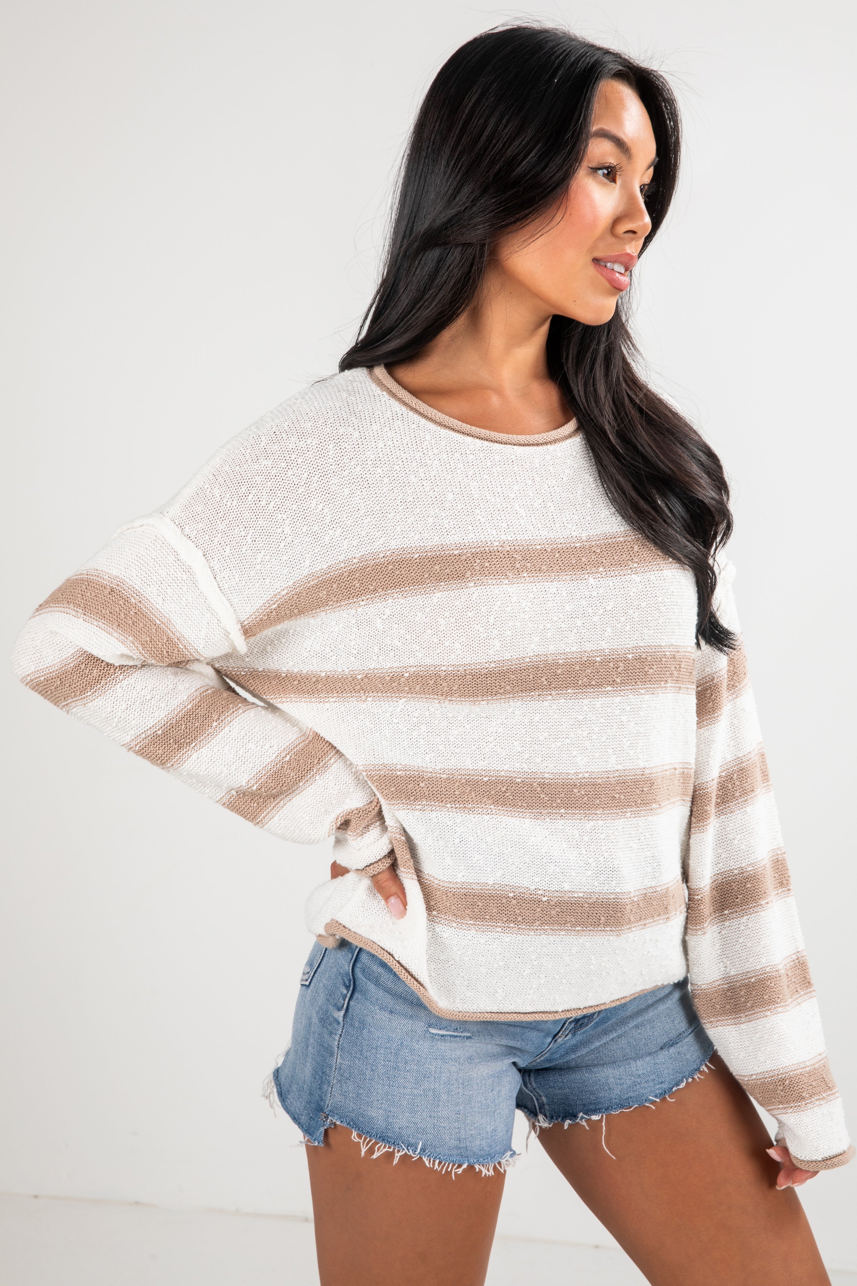 Woman wearing a striped sweater and denim shorts on a white background