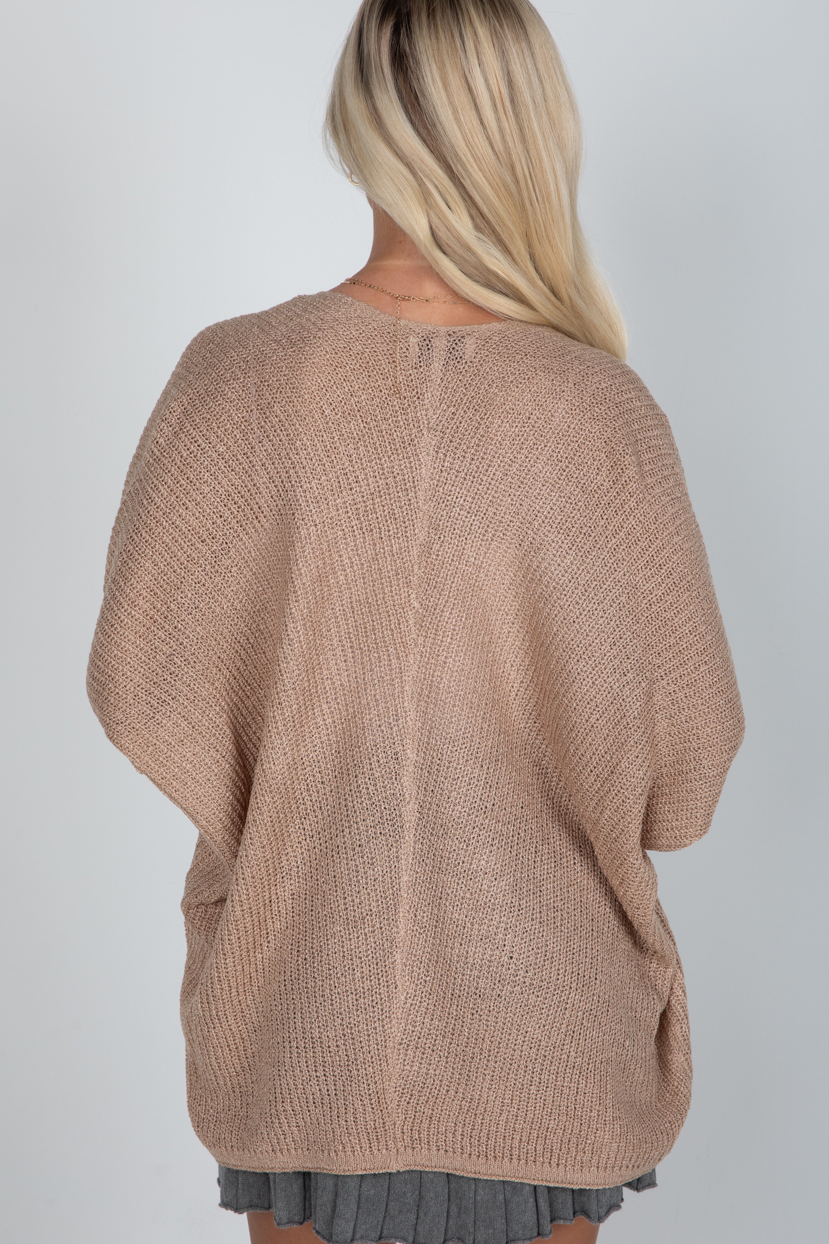 Person wearing a beige sweater on a plain background