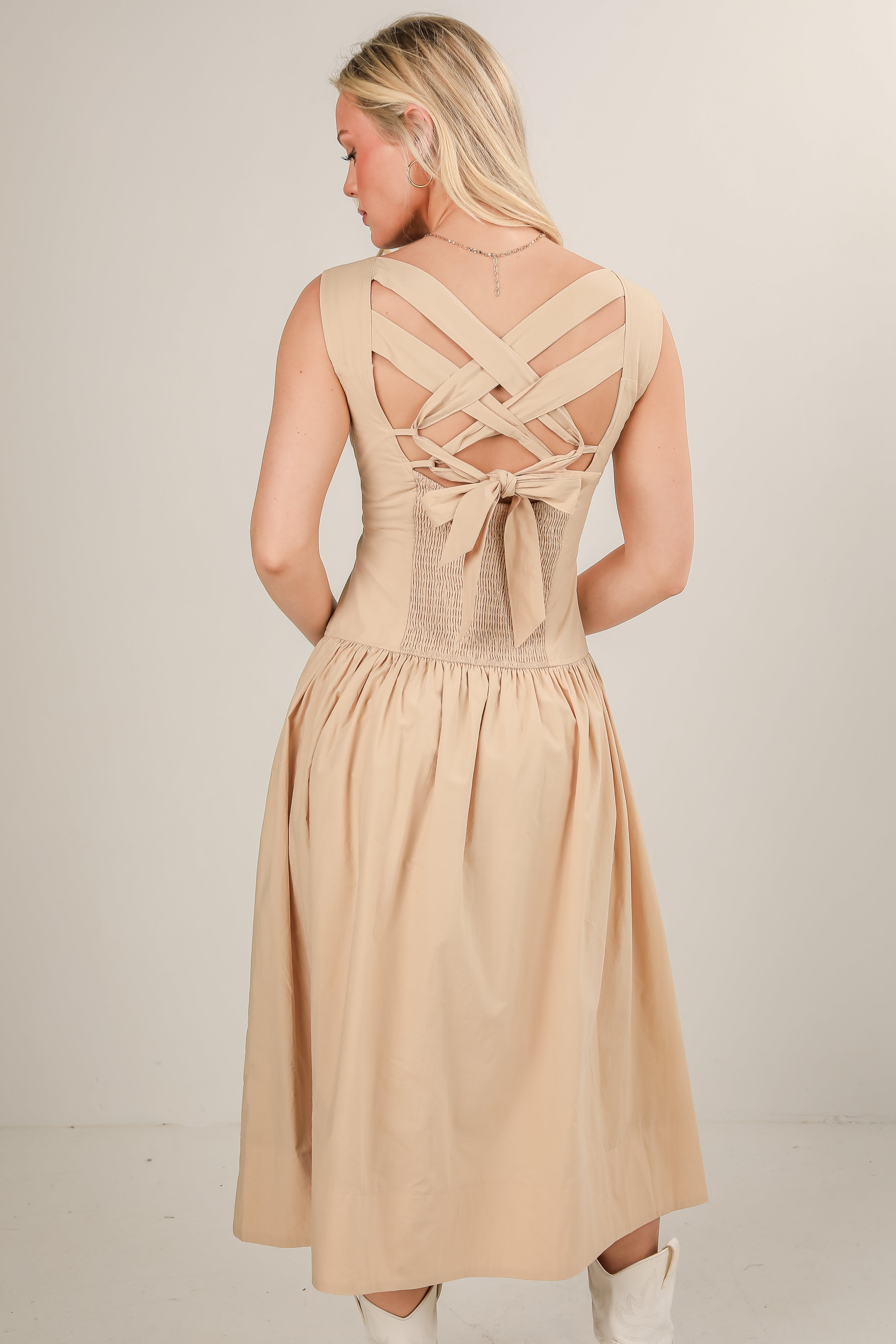 Beige dress with criss-cross back design on a plain background