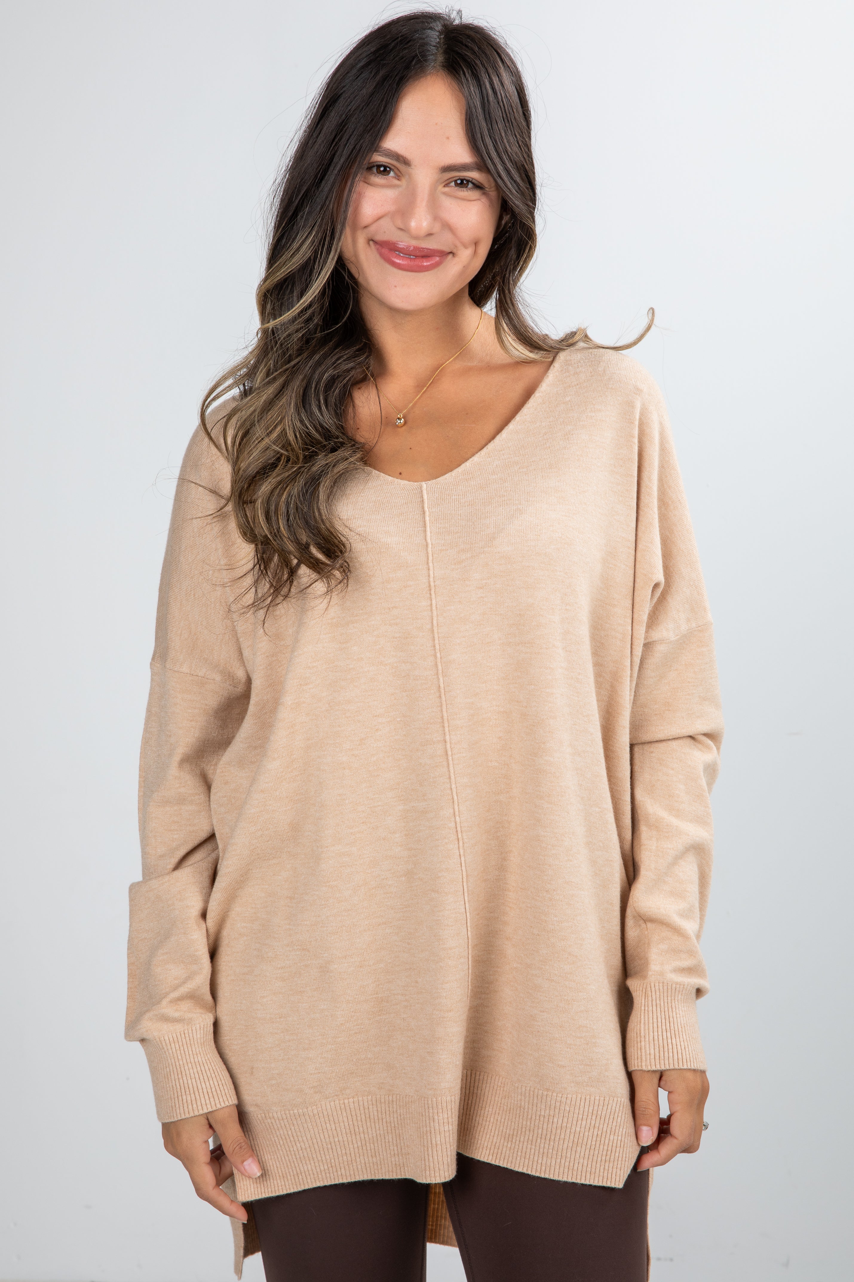 Woman wearing a beige sweater against a white background