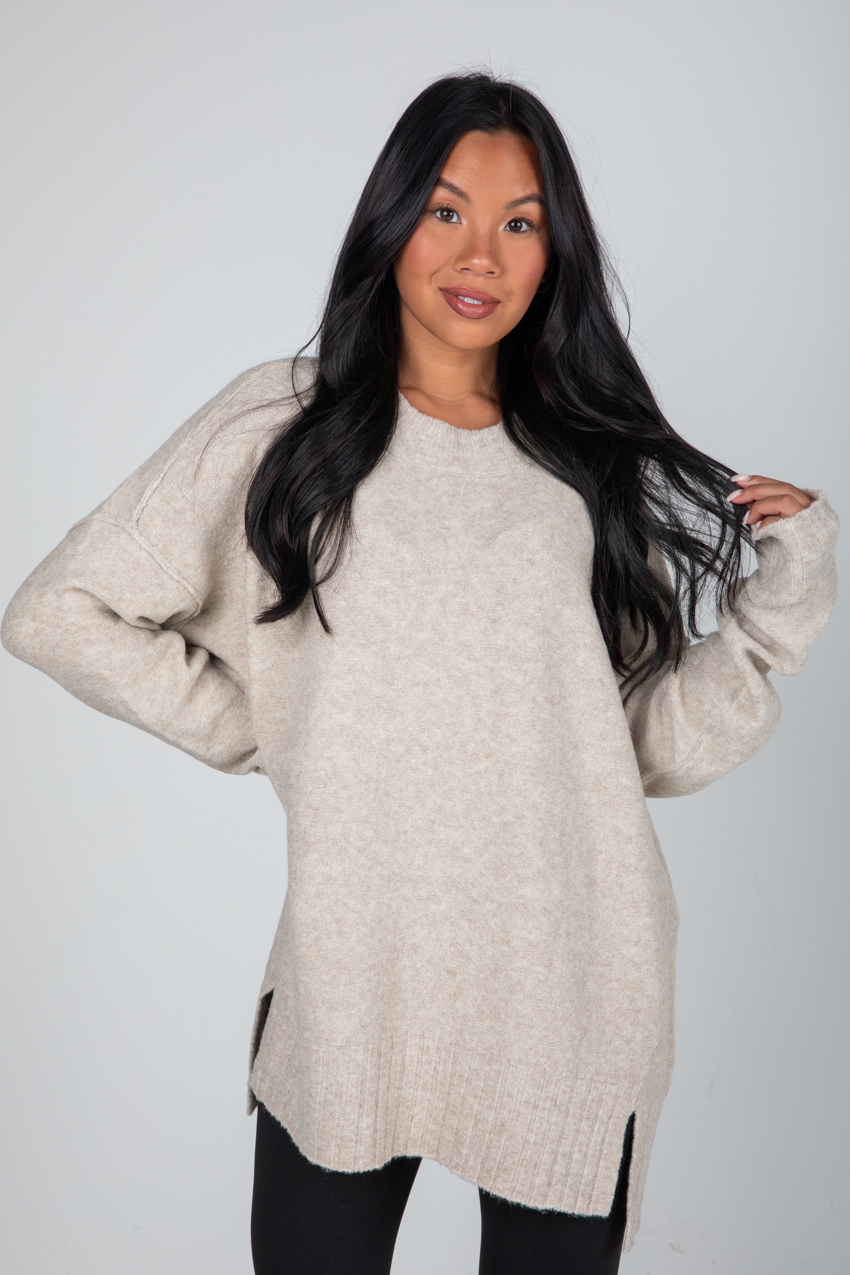 Woman wearing a beige sweater against a plain background