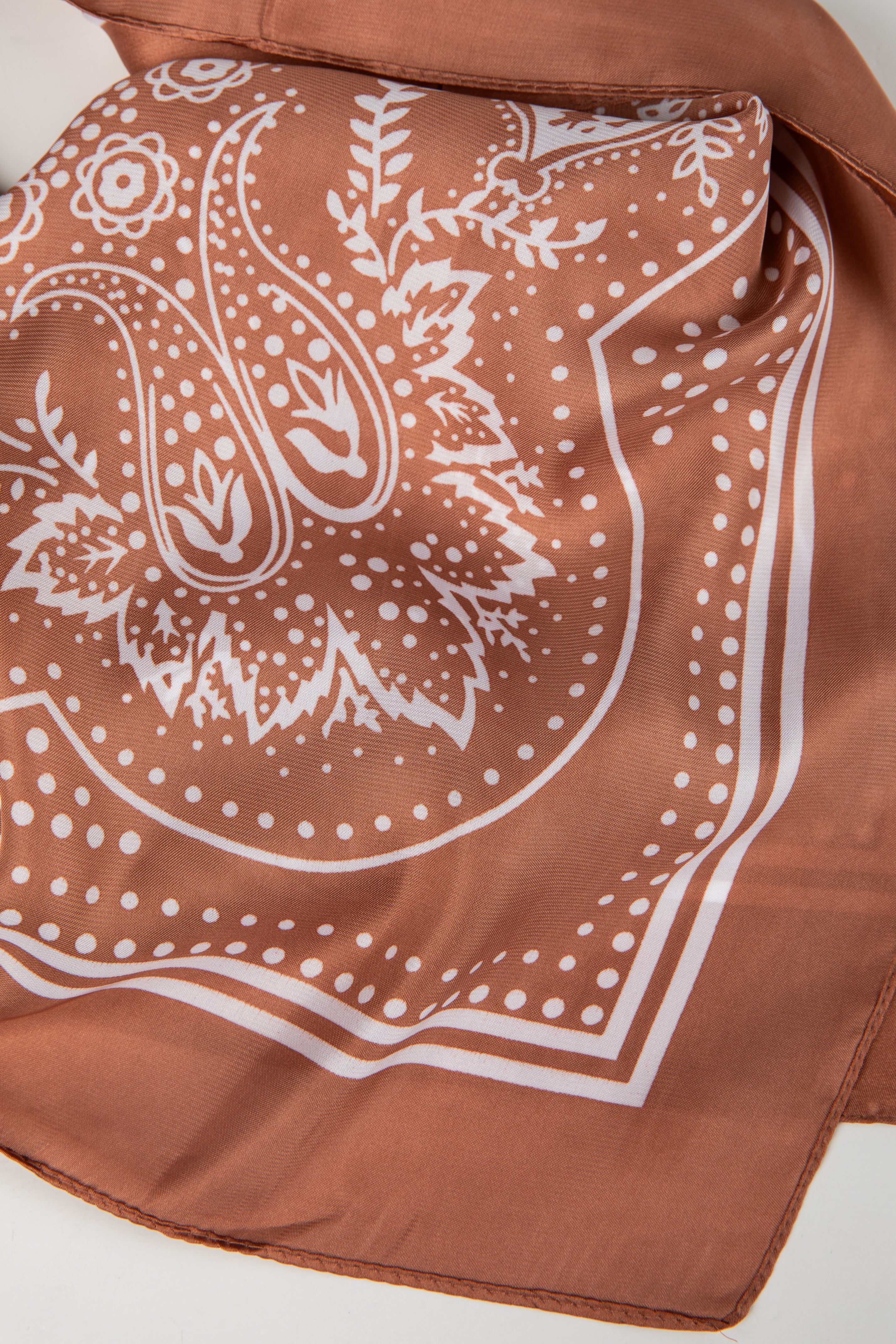 Brown bandana with white paisley pattern on a white background