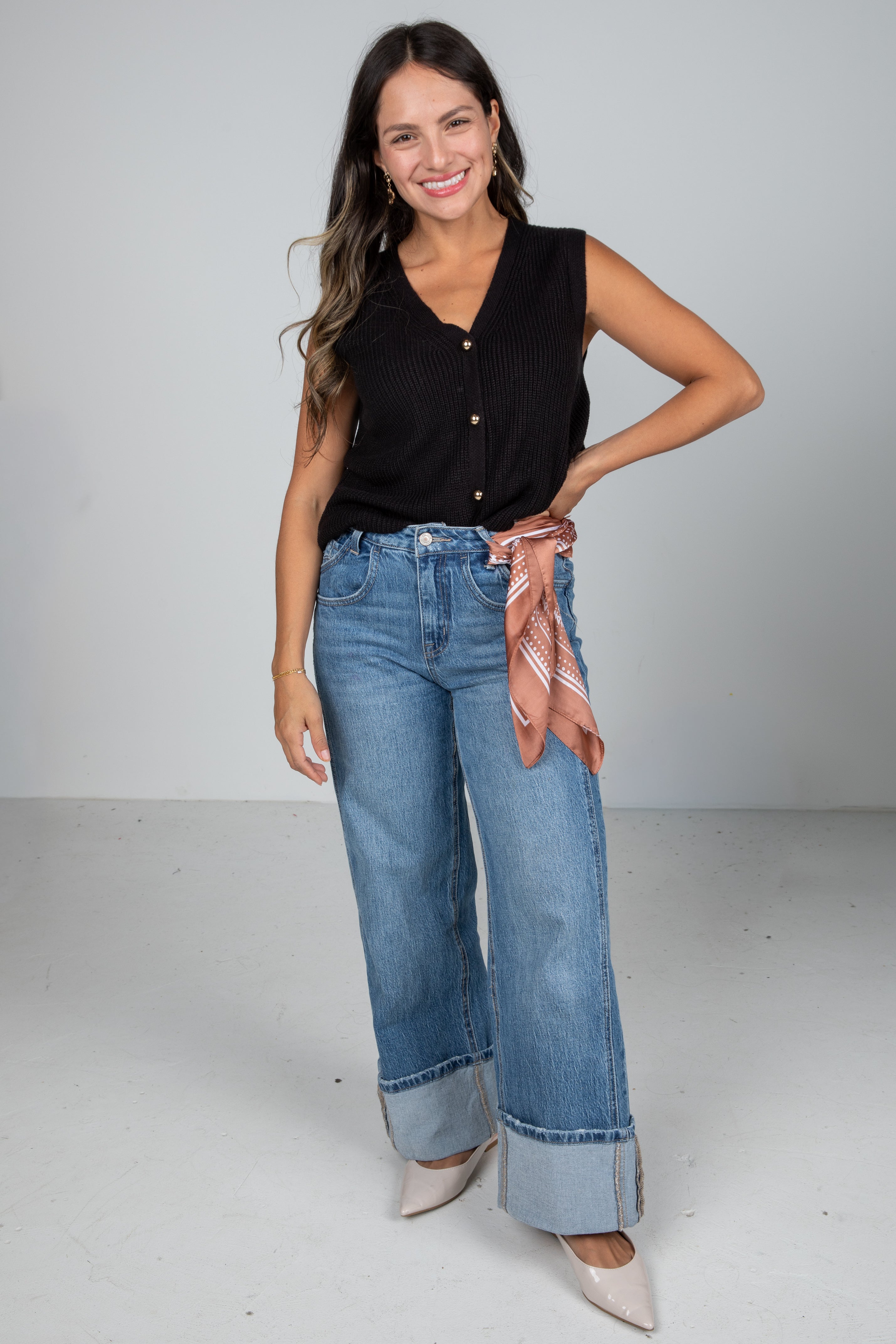 Woman wearing a black top and blue jeans with a white background