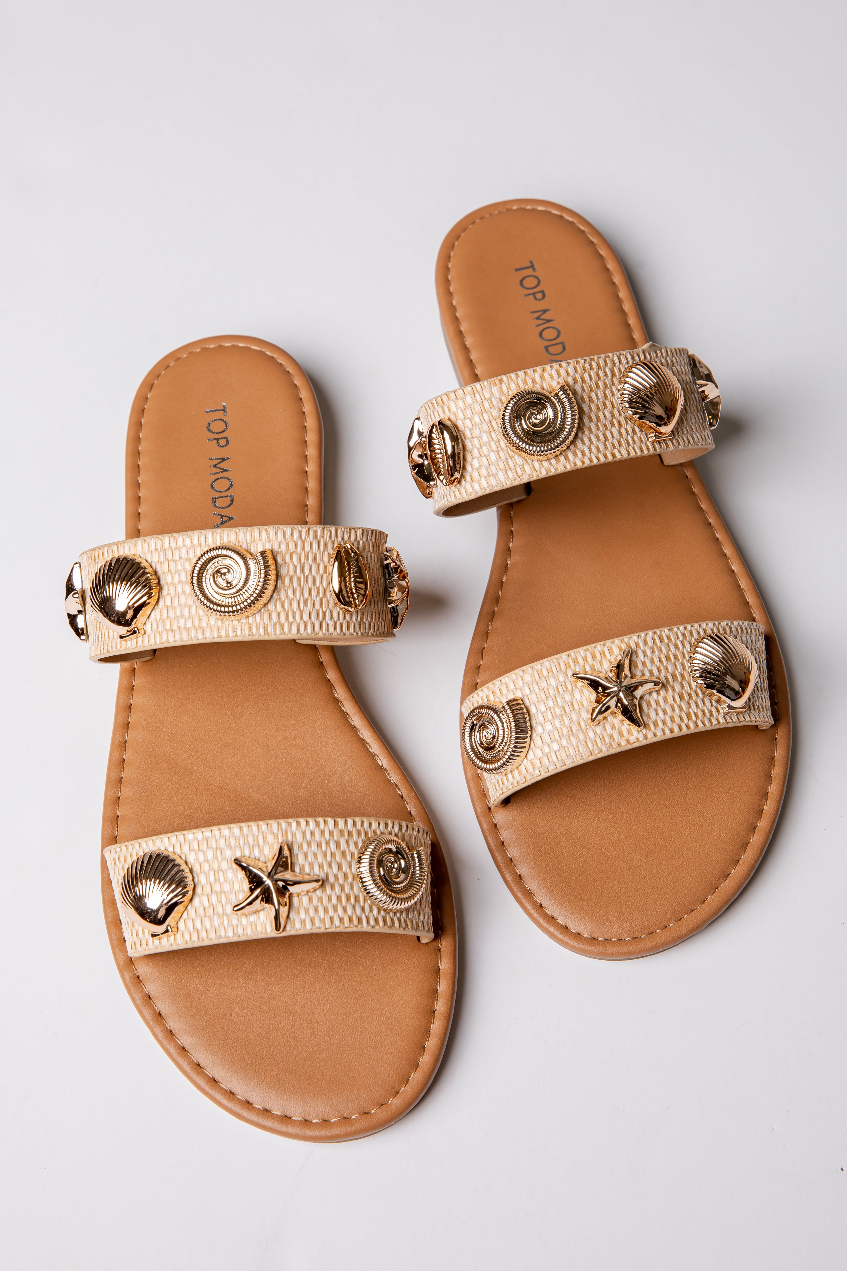 Pair of tan sandals with gold embellishments on a light gray background