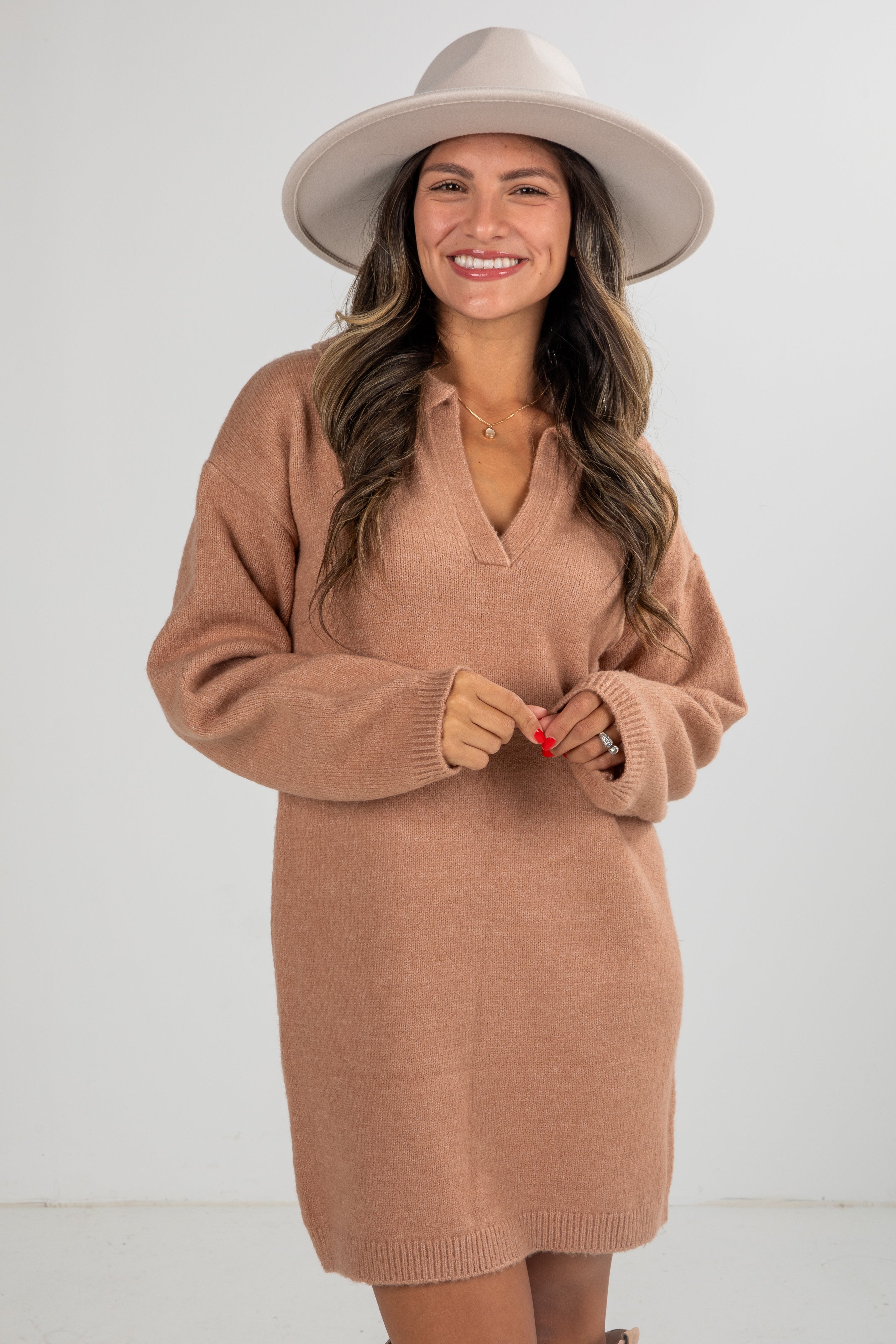 Woman wearing a brown sweater dress and beige hat on a white background