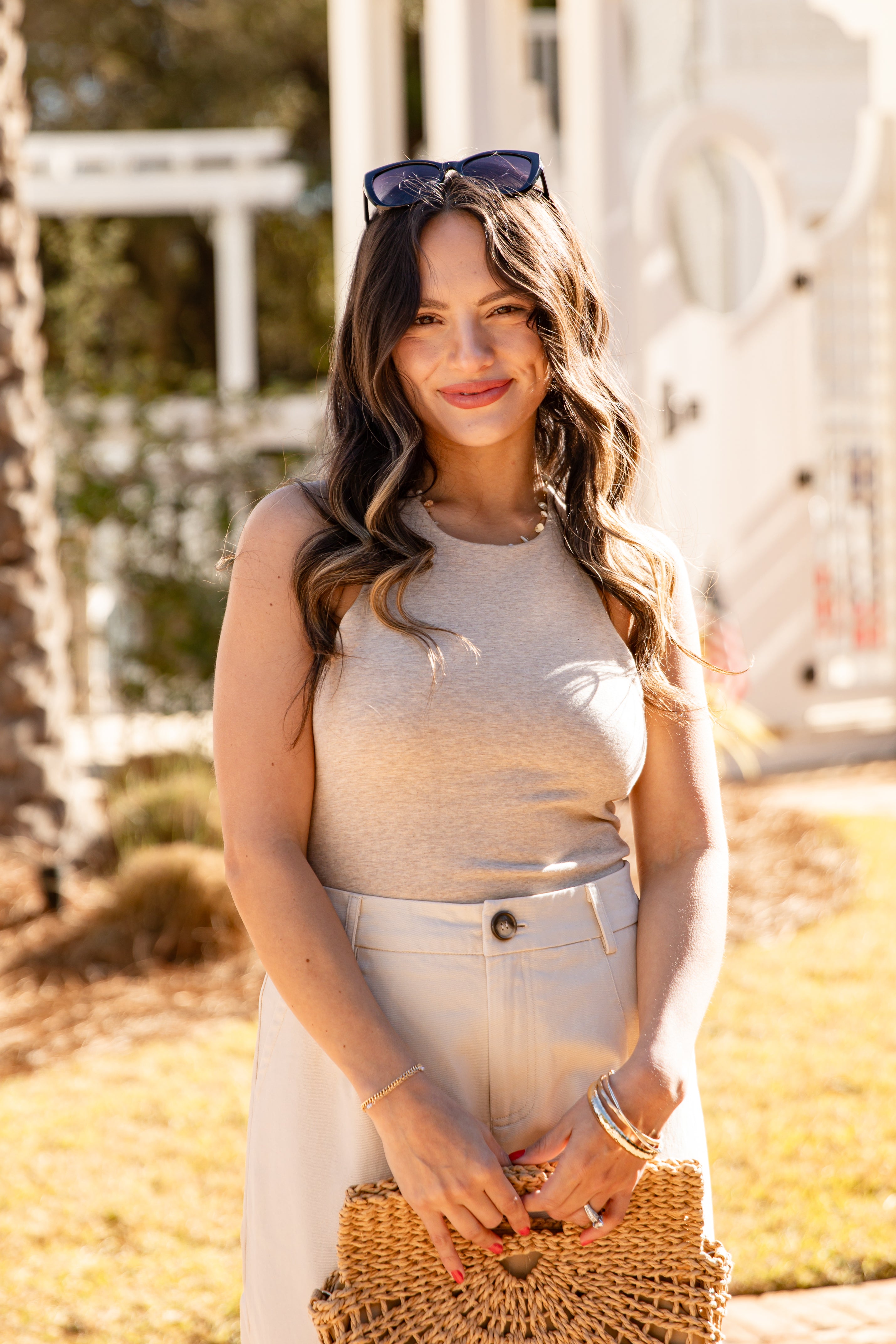Woman holding a woven clutch in an outdoor setting