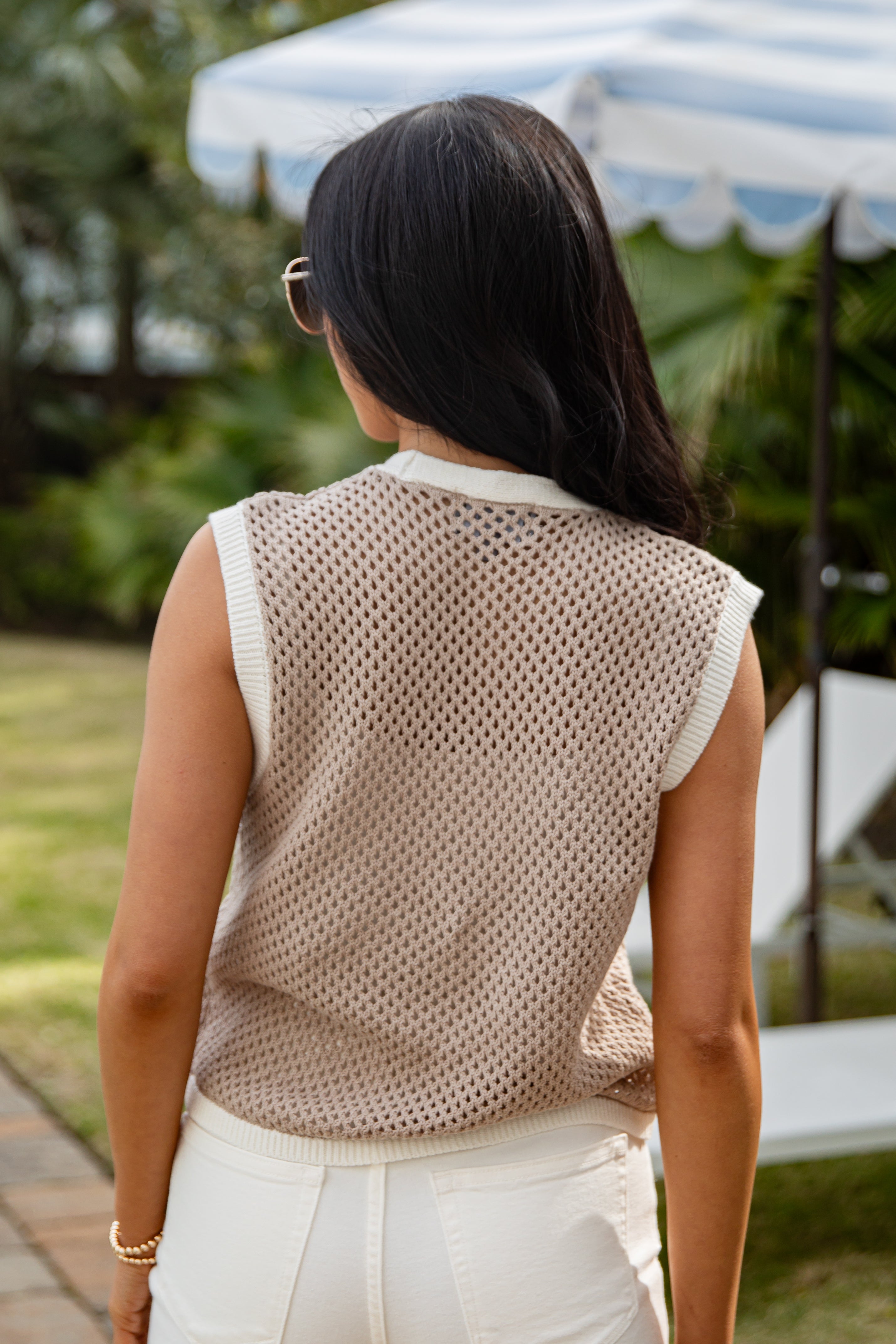 Woman wearing a beige mesh top and white pants outdoors