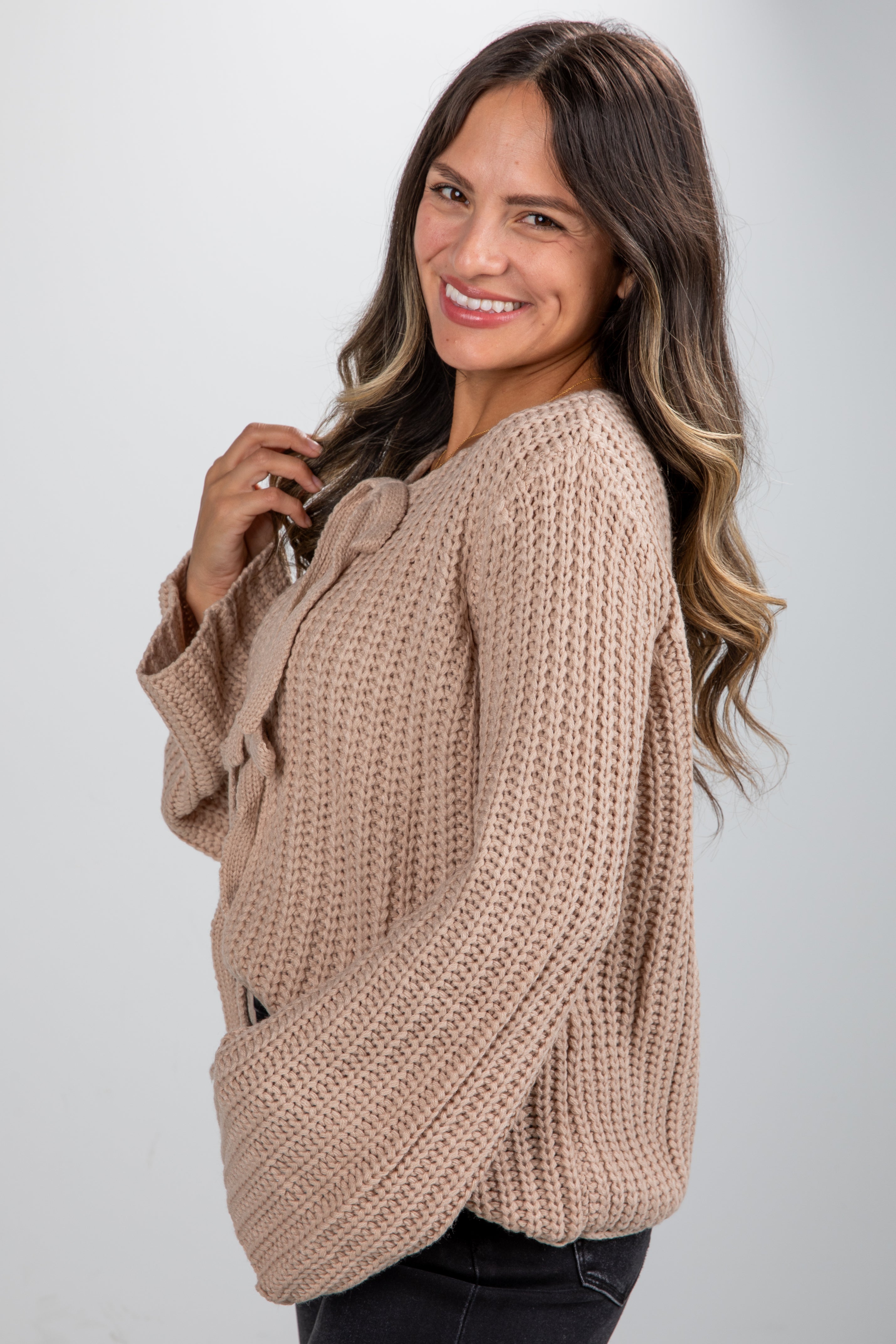 Woman wearing a beige knitted sweater against a plain background